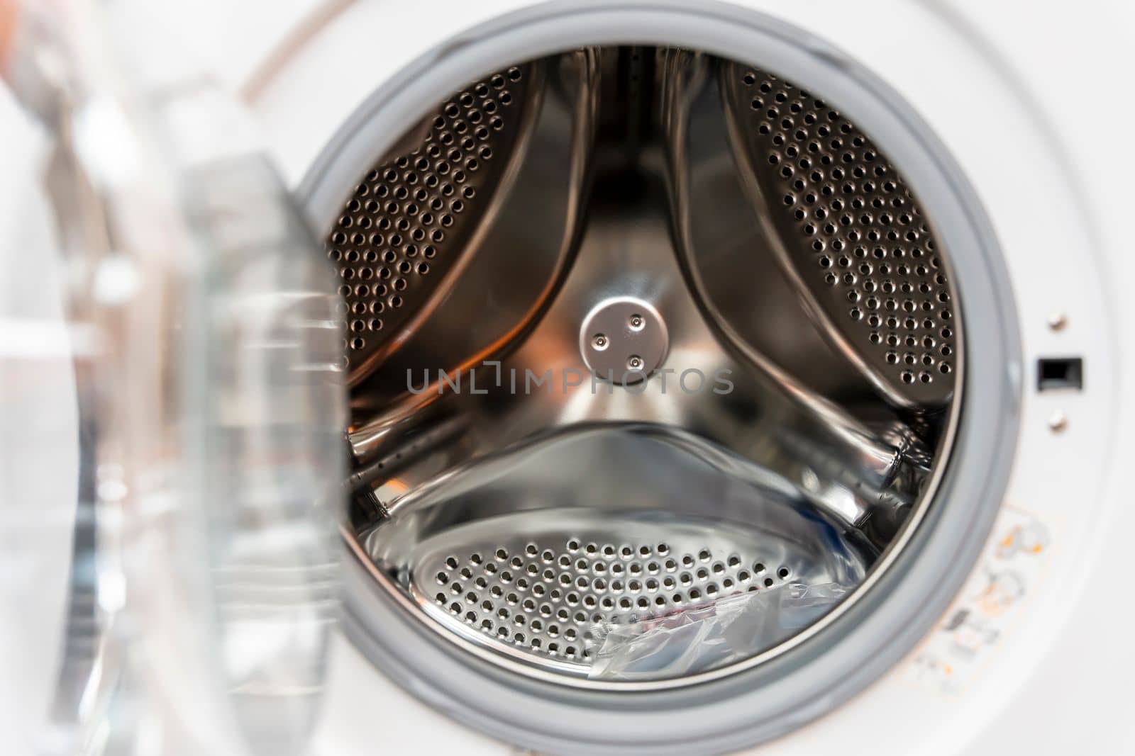 close-up of the metal drum of a modern washing machine. The open plastic door of the washing machine with a perforated stainless steel drum. technologies. close-up