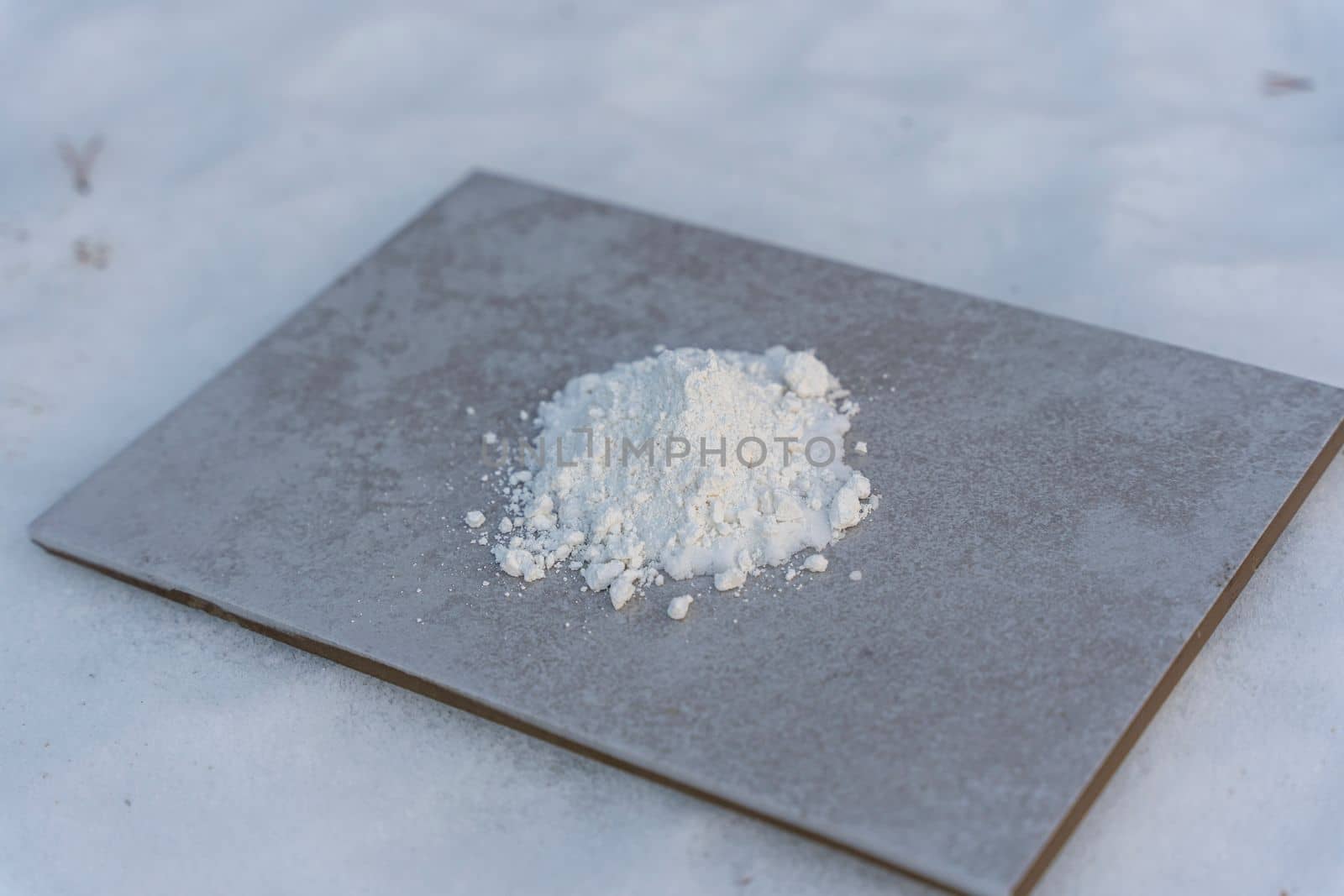 A white chemical powder is poured on a ceramic tile. chemical experiment with urotropin and calcium gluconate. Chemical experiments
