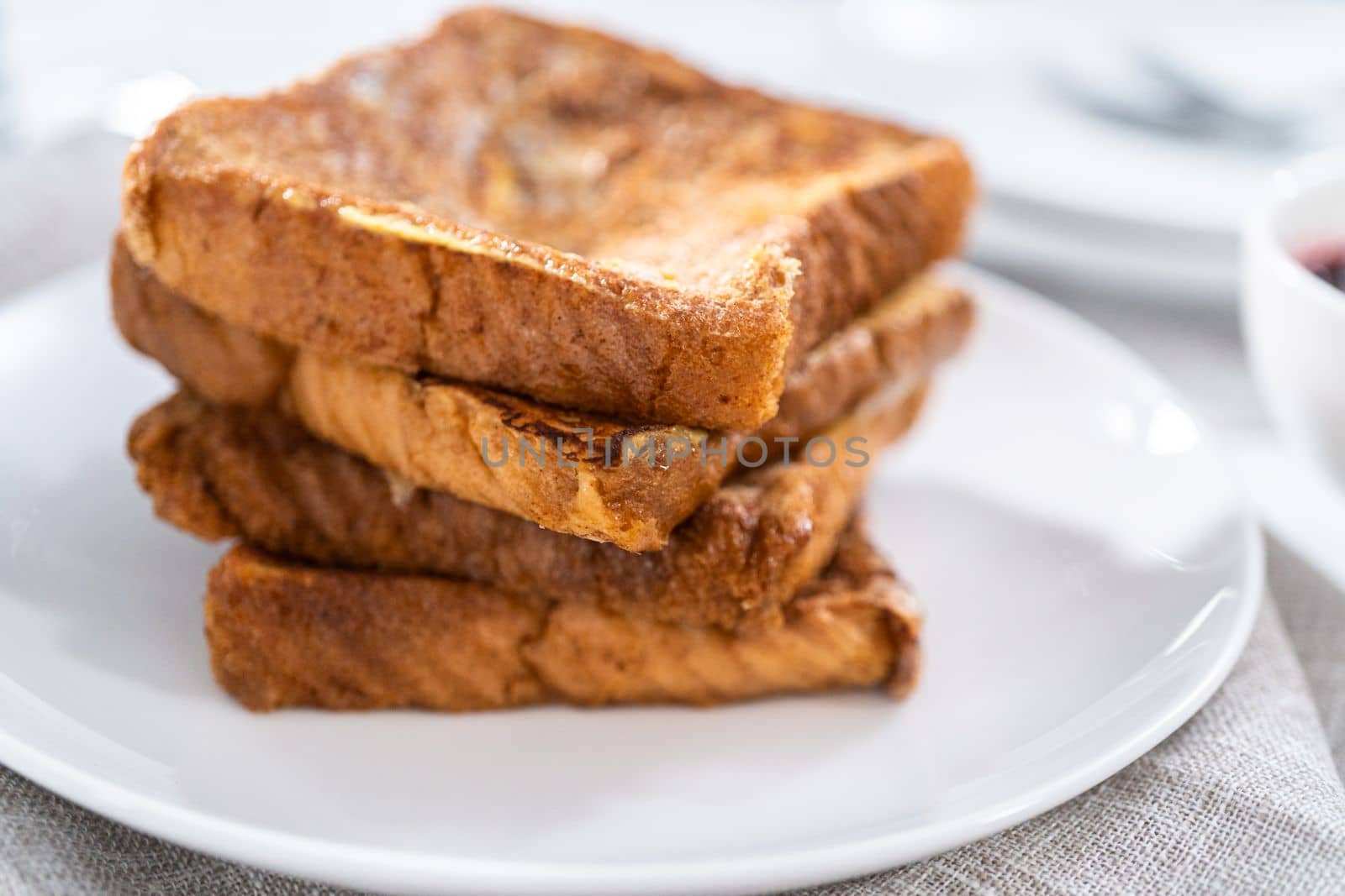 Stack of freshly baked french toast on a white plate.