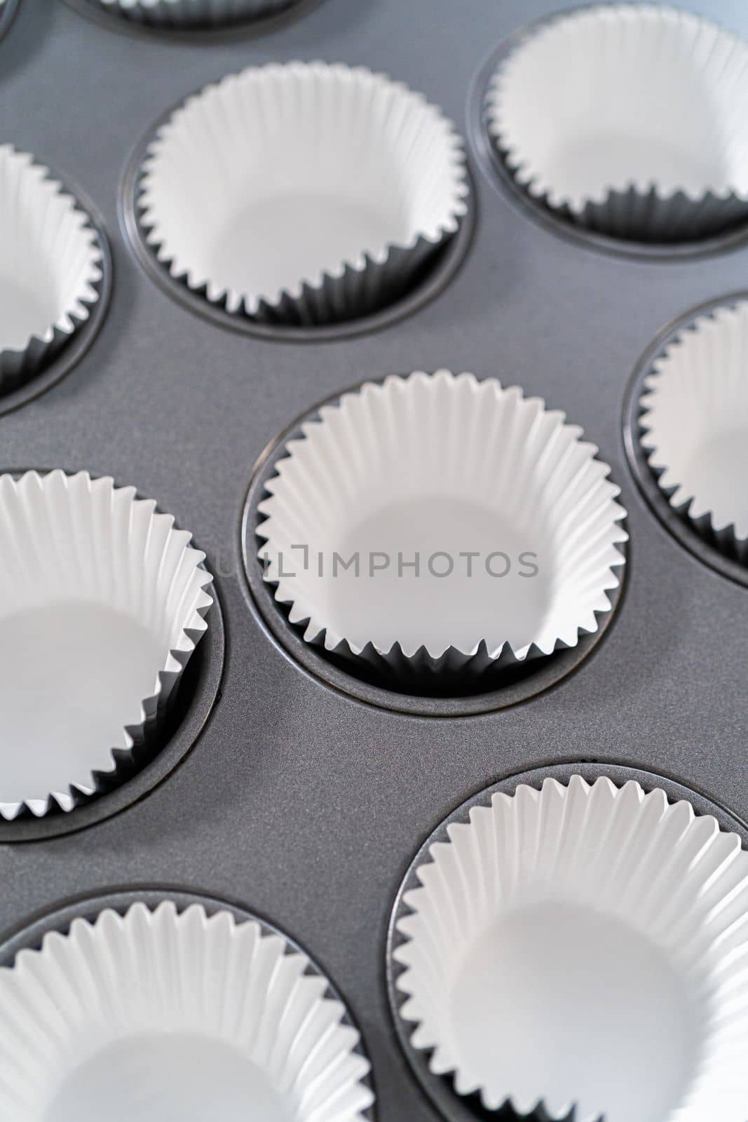 Lining baking cupcake pan with foil liners to bake lemon cupcakes.