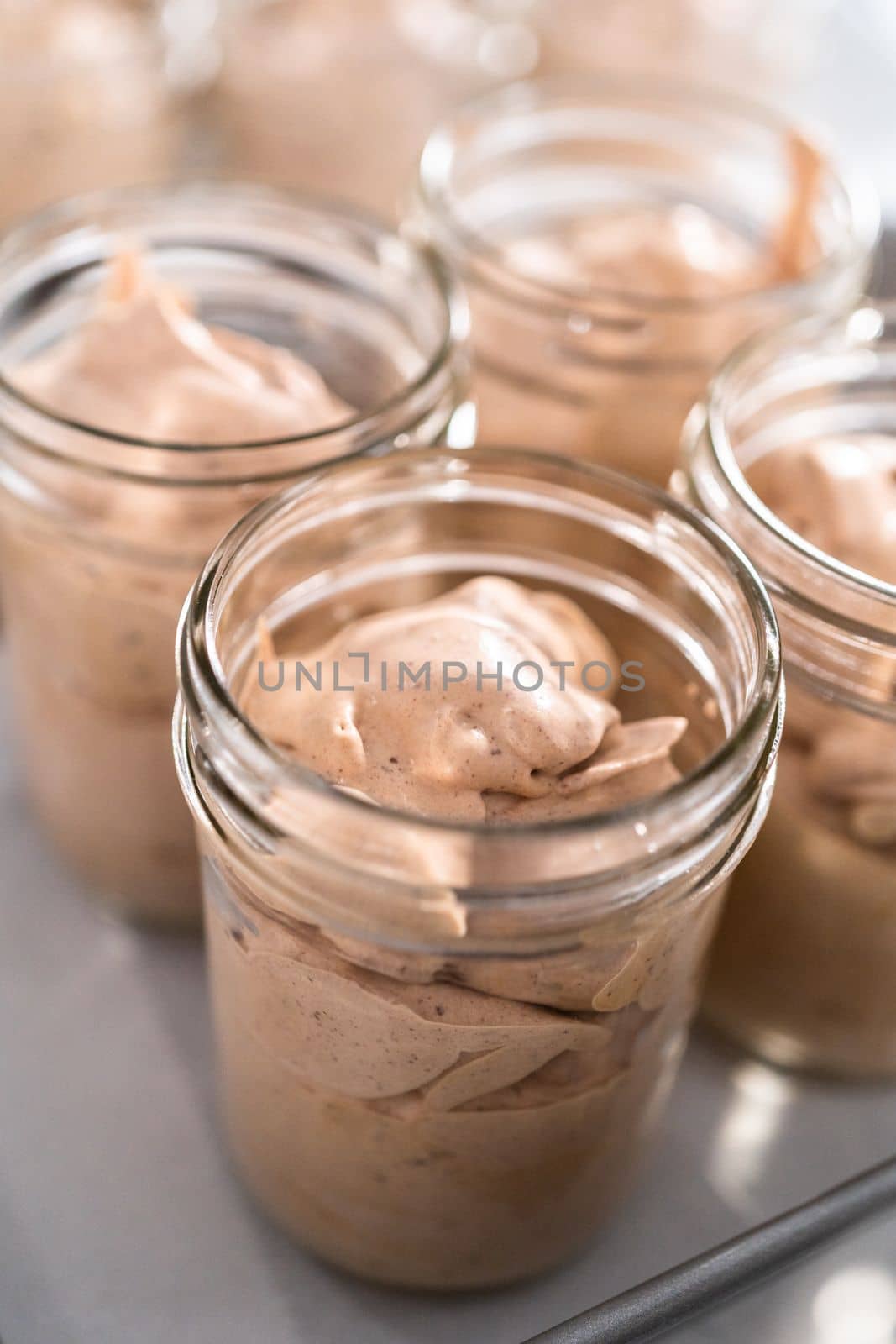 Scooping mixture into the small glass jars to make homemade chocolate ice cream.