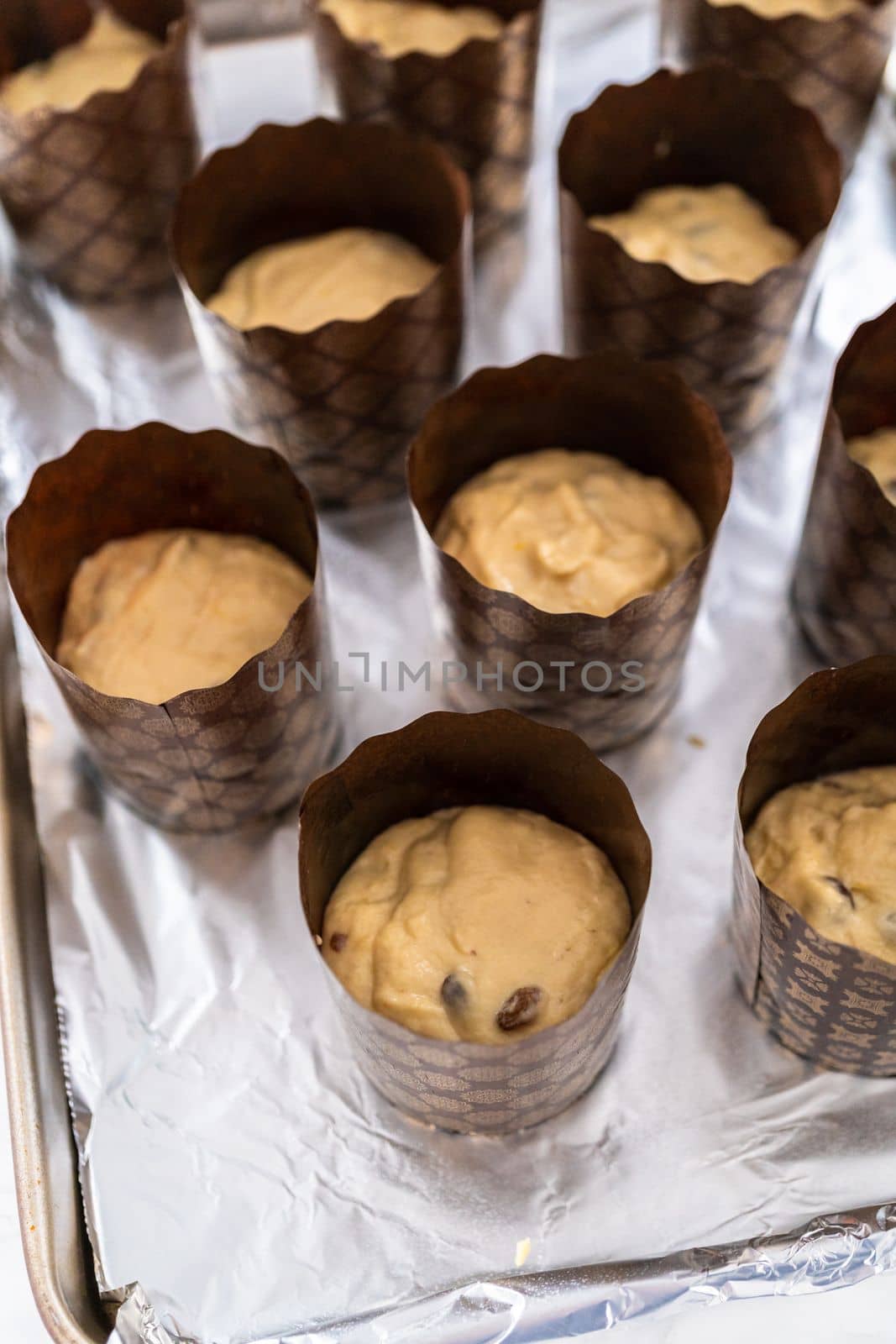 Rising dough in paper liners to bake mini Easter bread kulich.
