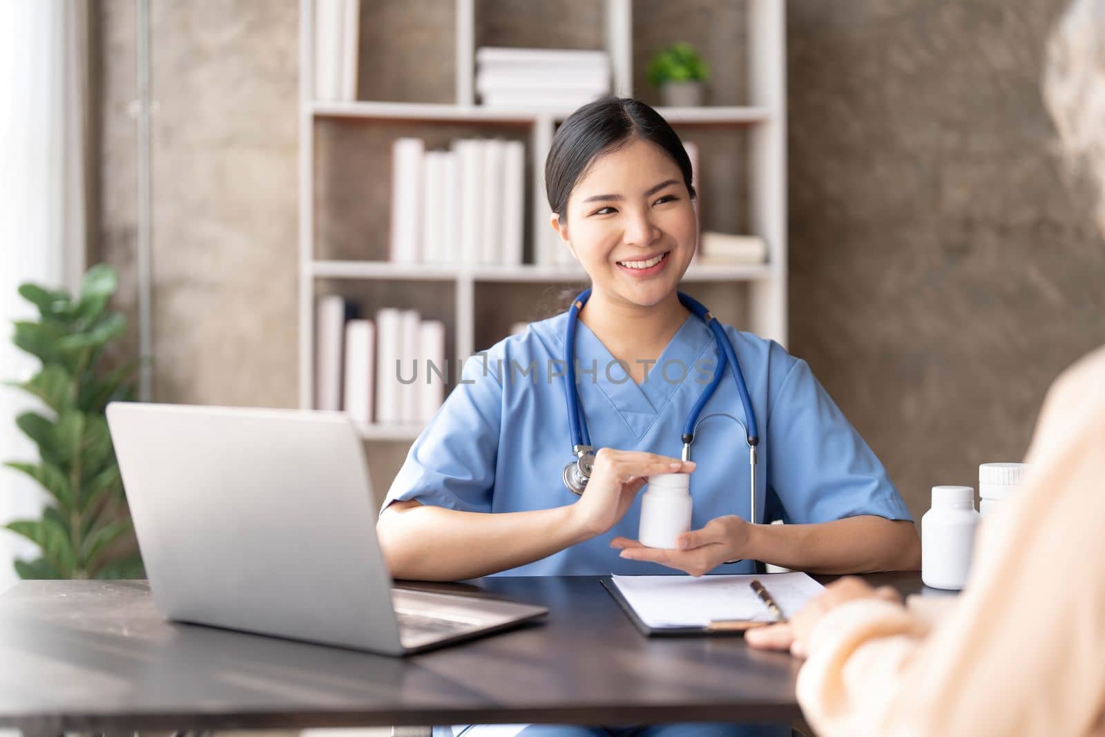 Asian Senior elderly female patient consult with physician nurse at nursing home care. Caregiver therapist pharmacist girl hold medicine pills bottle, explain prescription to older disabled guy in house