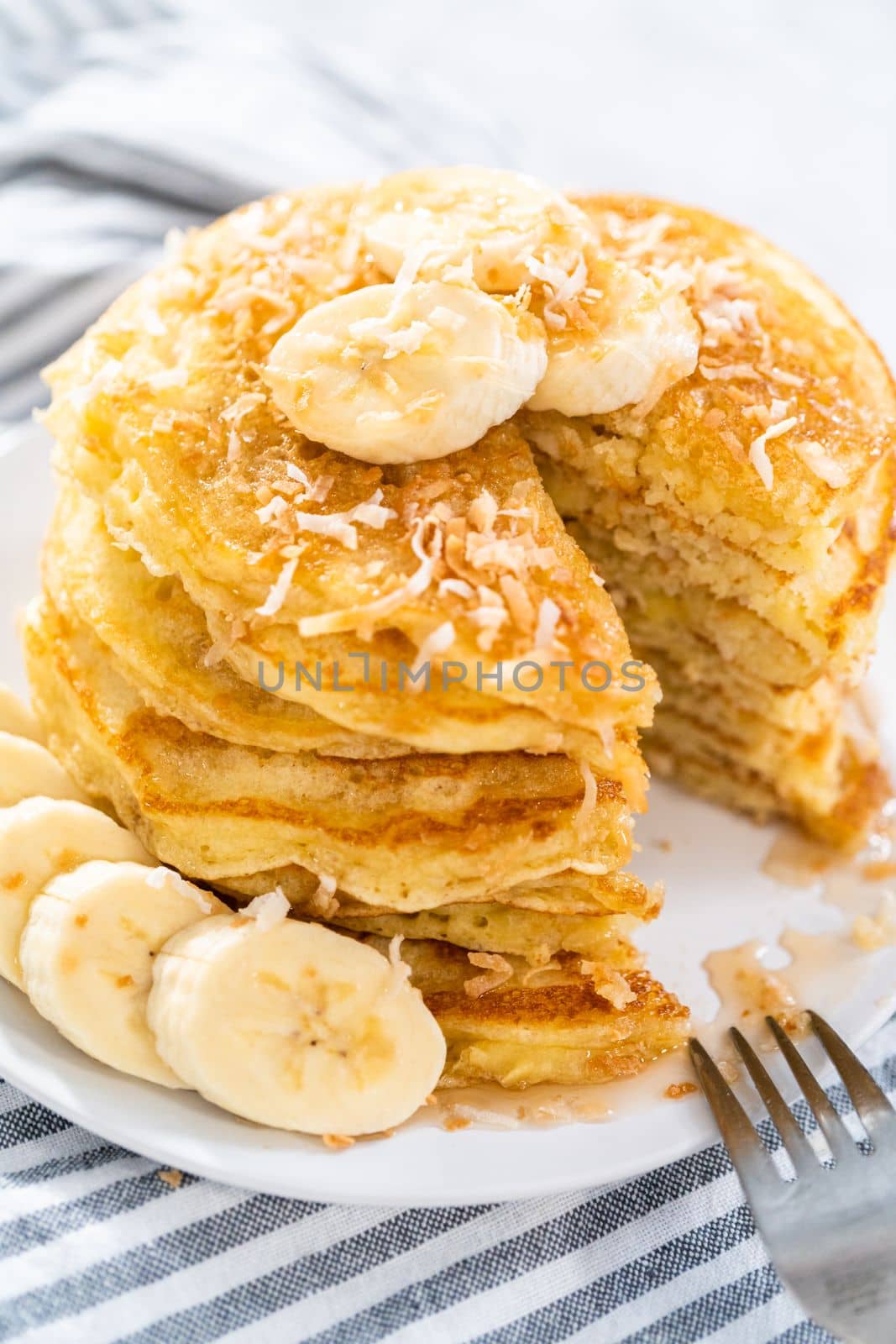 Eating freshly baked coconut banana pancakes garnished with sliced bananas and toasted coconut.