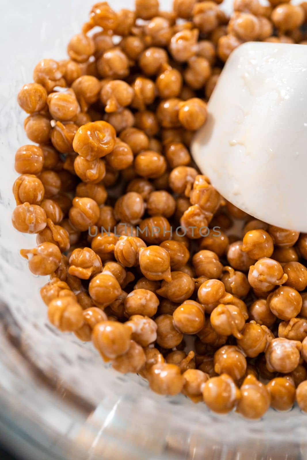 Melting chocolate chips and other ingredients in a glass mixing bowl over boiling water to prepare caramel fudge.