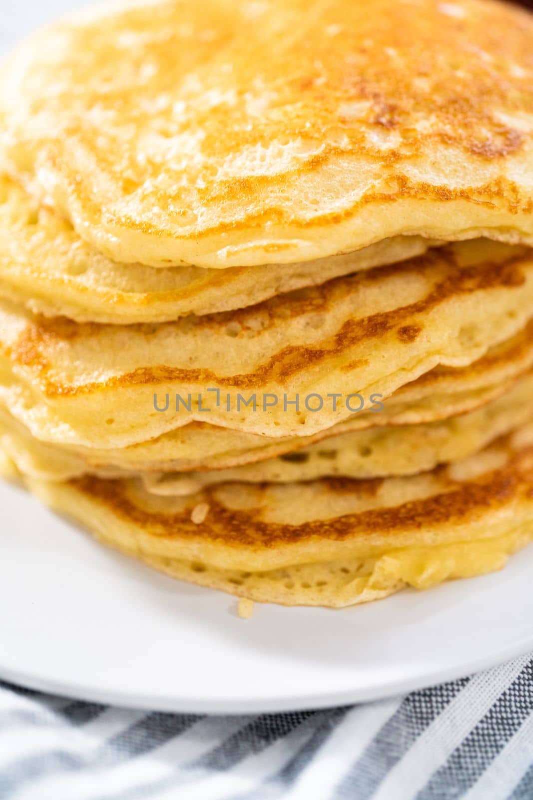 Stack of freshly baked coconut banana pancakes garnished with sliced bananas, toasted coconut, and maple syrup.