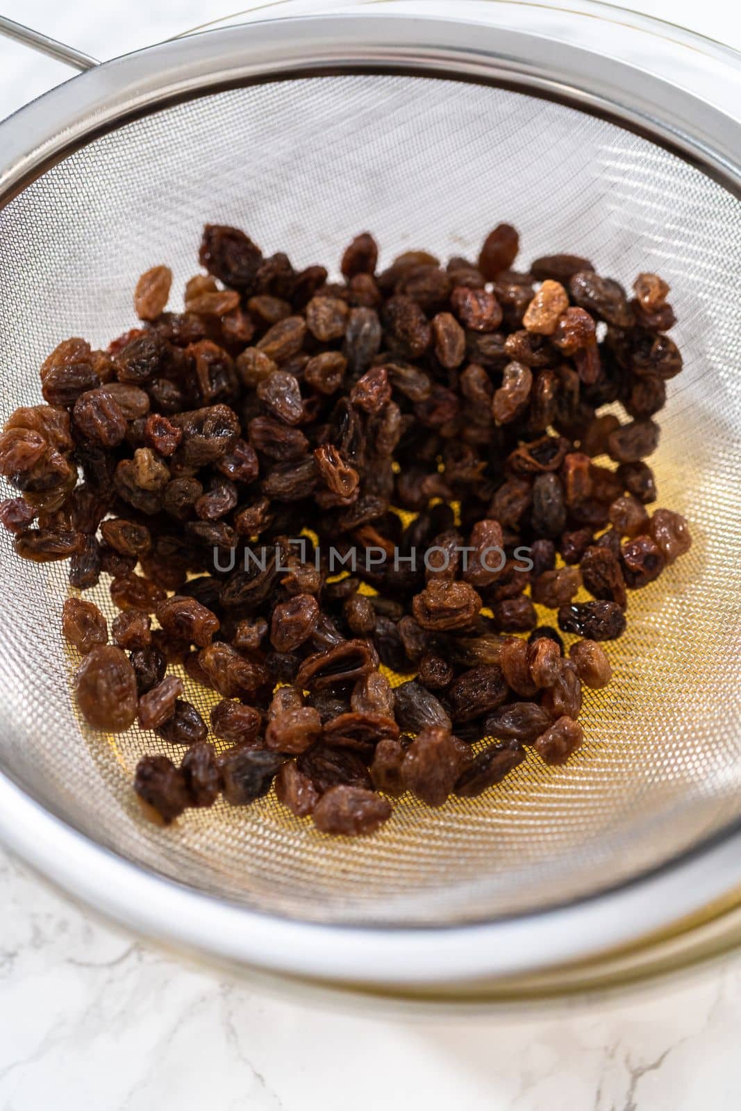 Soaking dried raisins in hot water to baking mini Easter bread kulich.