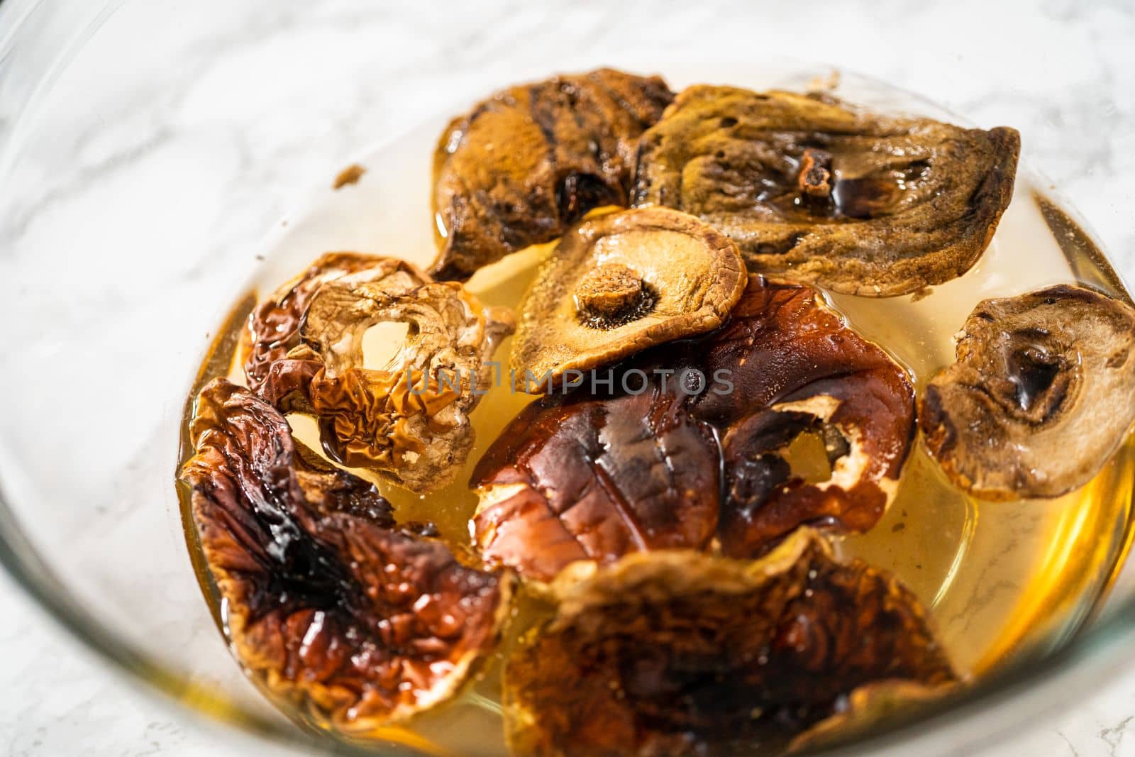 Soaking dehydrated wild mushrooms in a glass mixing bowl with hot water.
