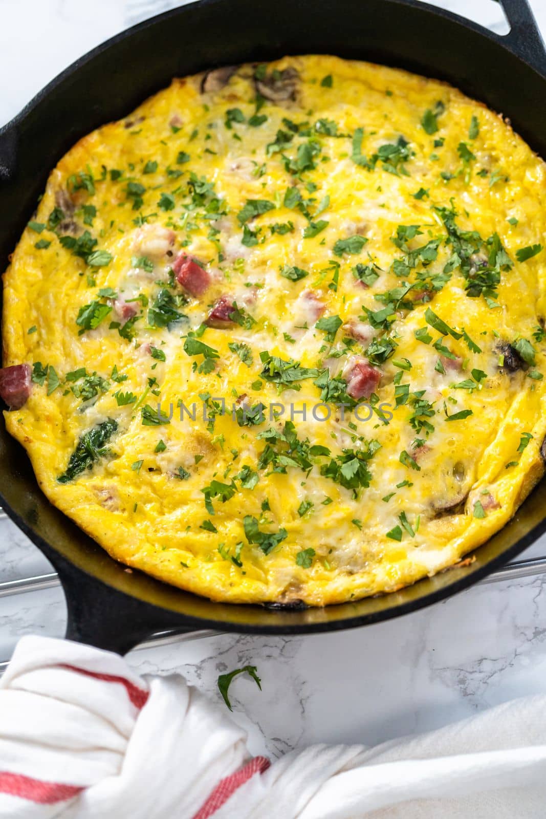 Freshly baked spinach and ham frittata in cast iron skillet.