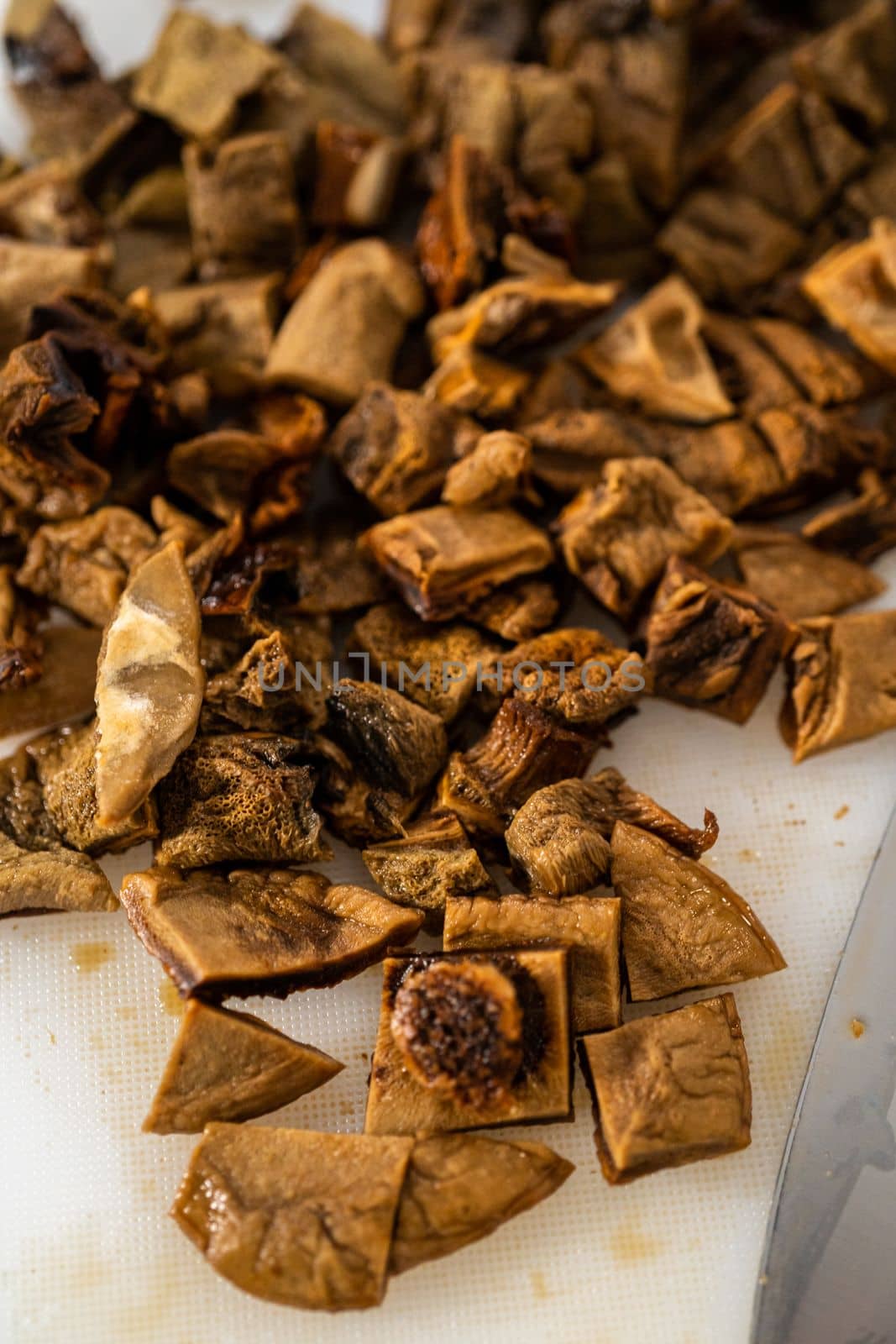 Cutting dehydrated wild mushrooms on a white cutting board.