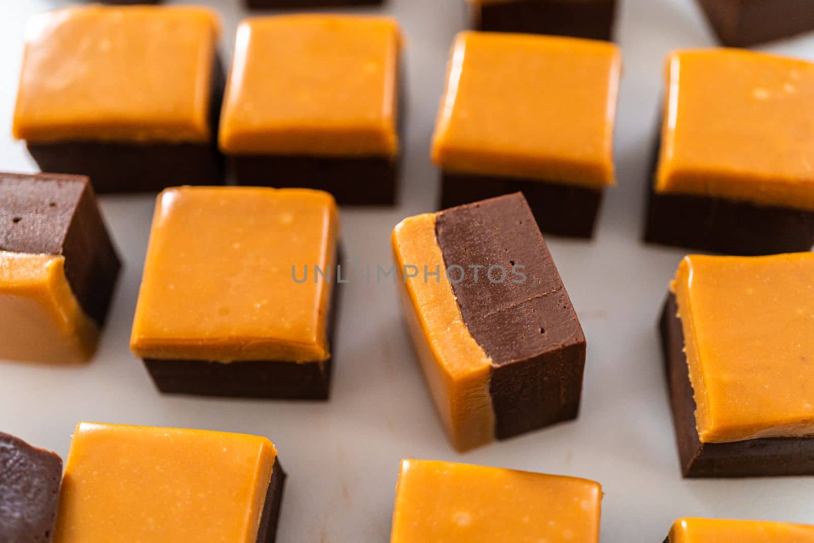 Homemade caramel fudge pieces on a white cutting board.
