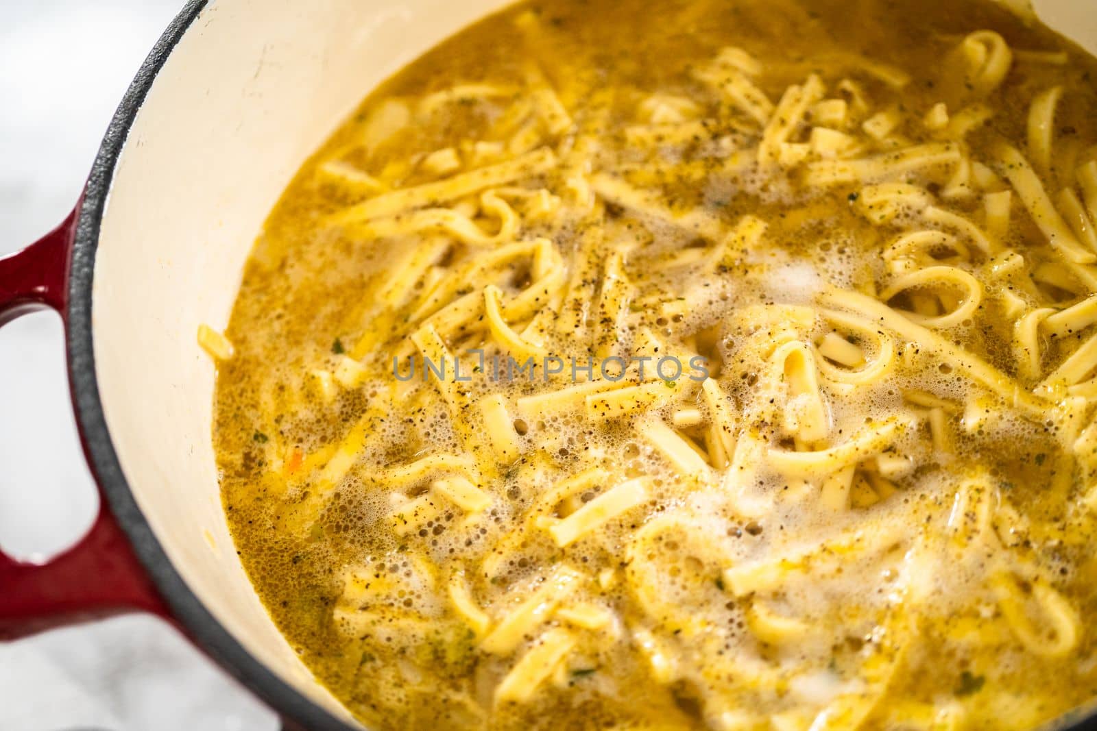 Cooking chicken noodle soup with kluski noodles in an enameled dutch oven.