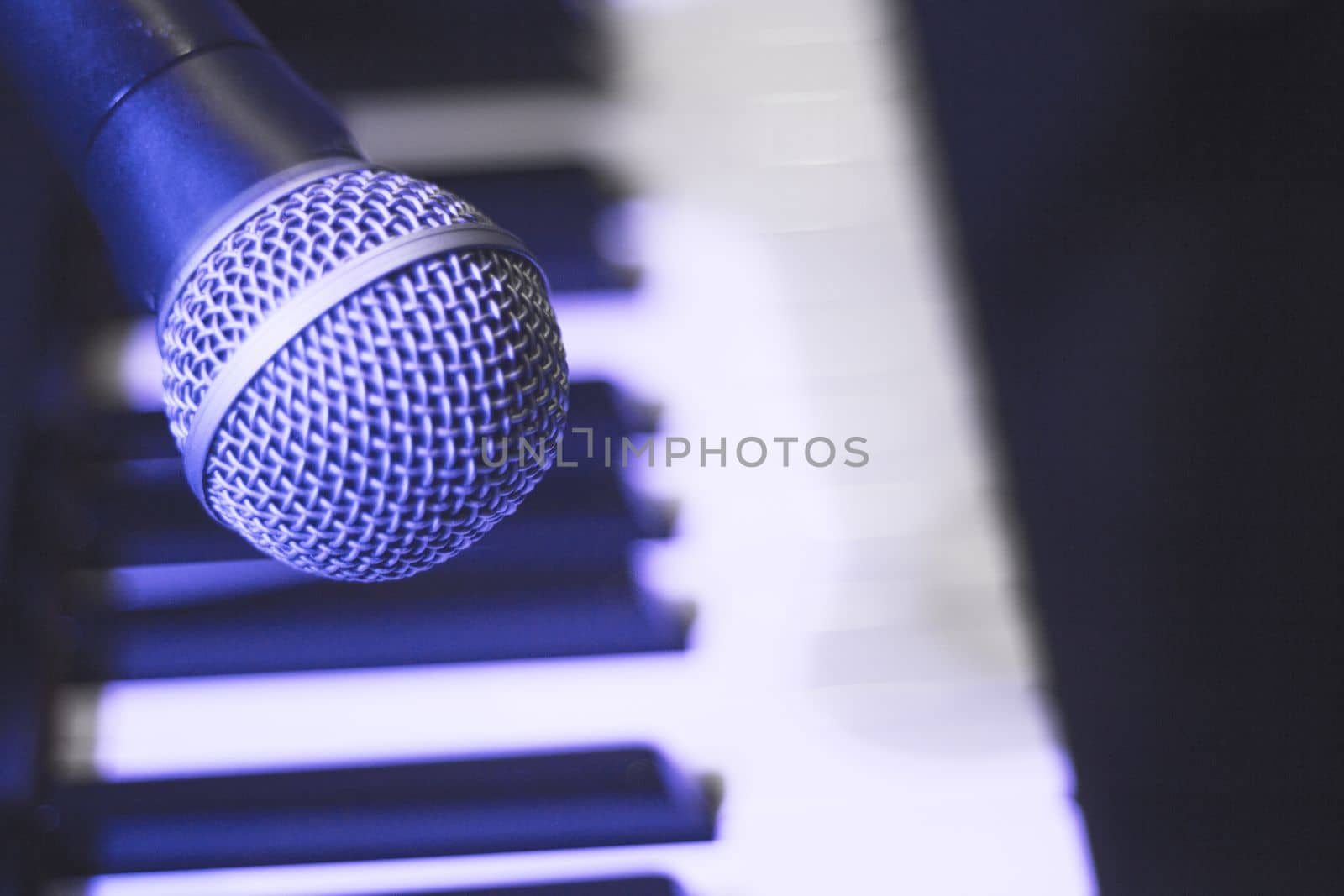 Microphone over piano keys in dim light. No people