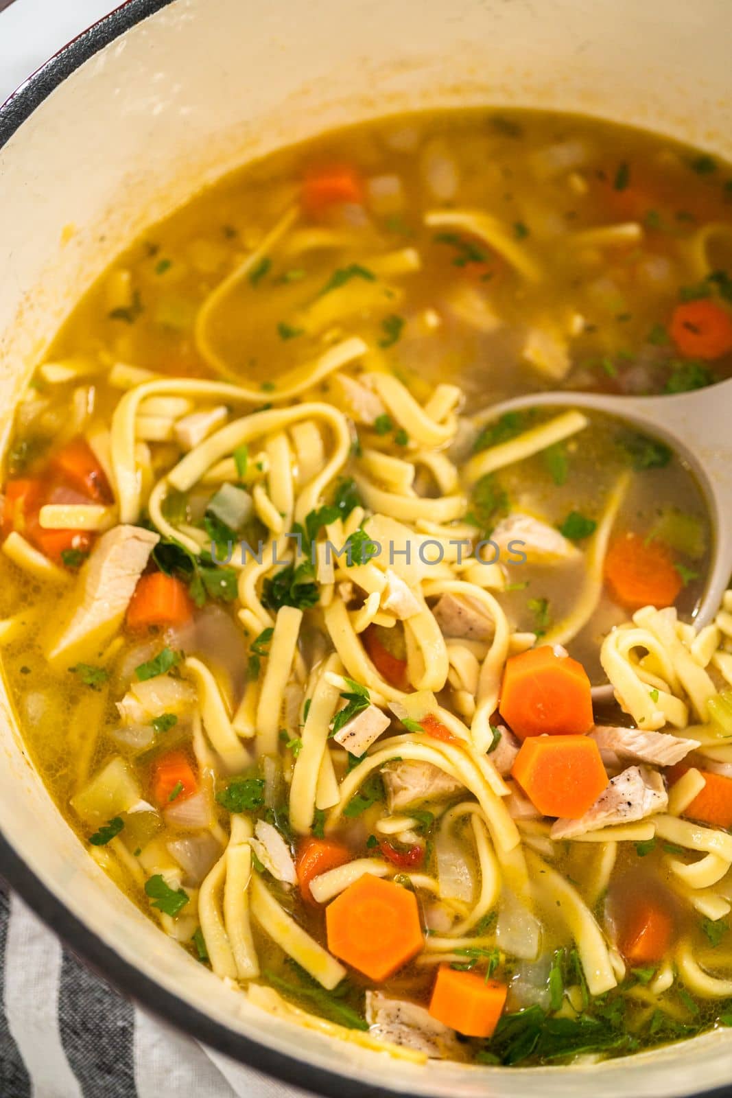 Serving chicken noodle soup with kluski noodles in white ceramic soup bowls.