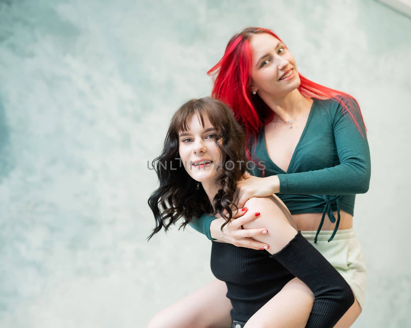 Two friends are fooling around. Young caucasian woman on the back of another