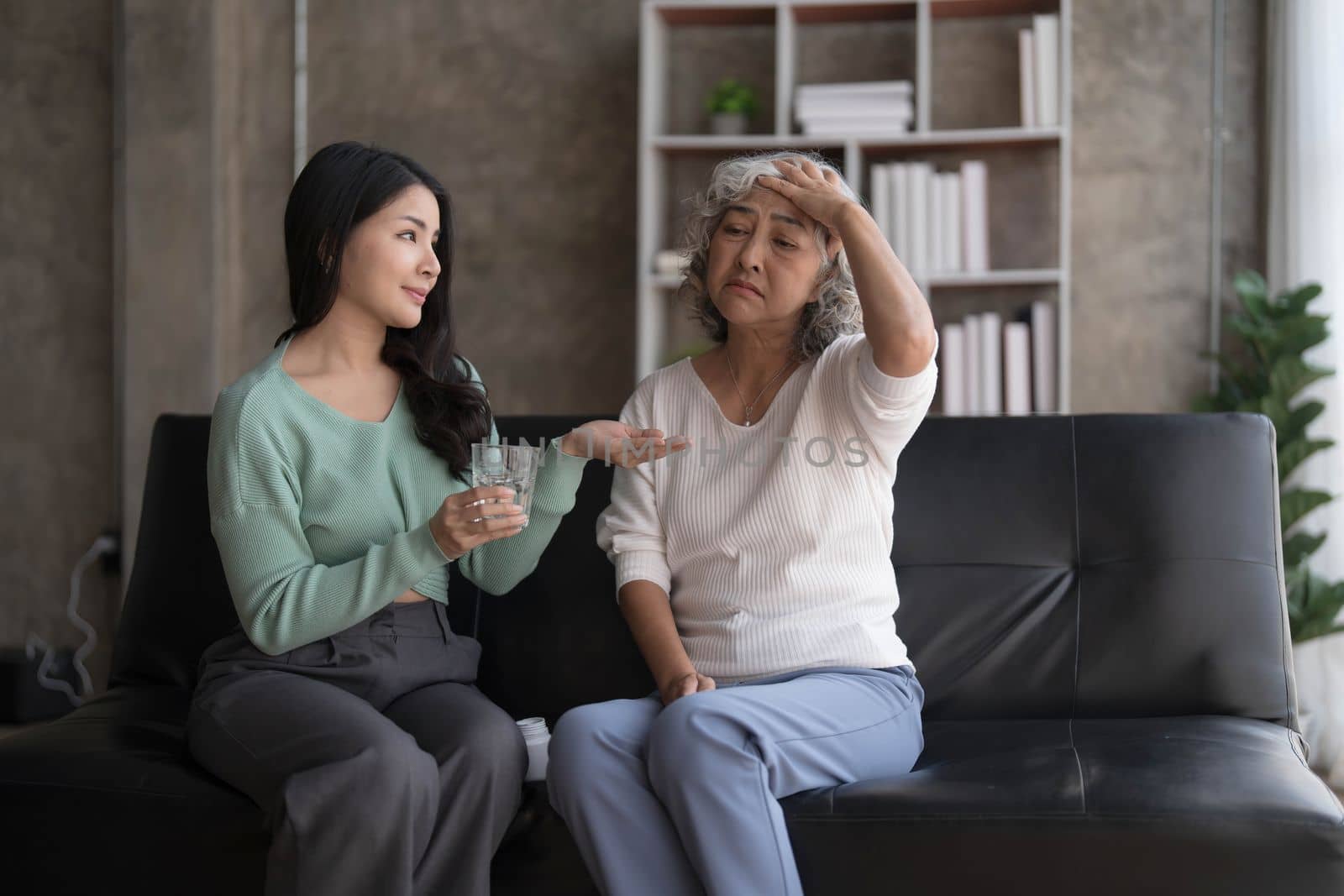 Young Asian woman taking care and giving a glass of water and taken daily medicine or vitamin supplements, elderly healthcare and grandmother. by wichayada