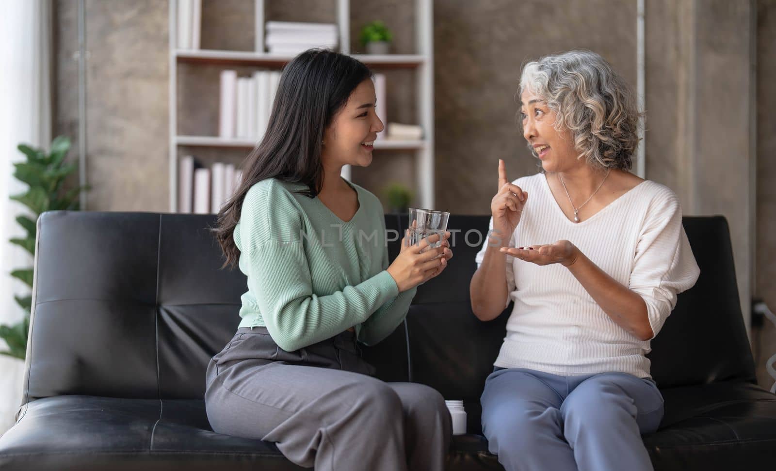 Young Asian woman taking care and giving a glass of water and taken daily medicine or vitamin supplements, elderly healthcare and grandmother...