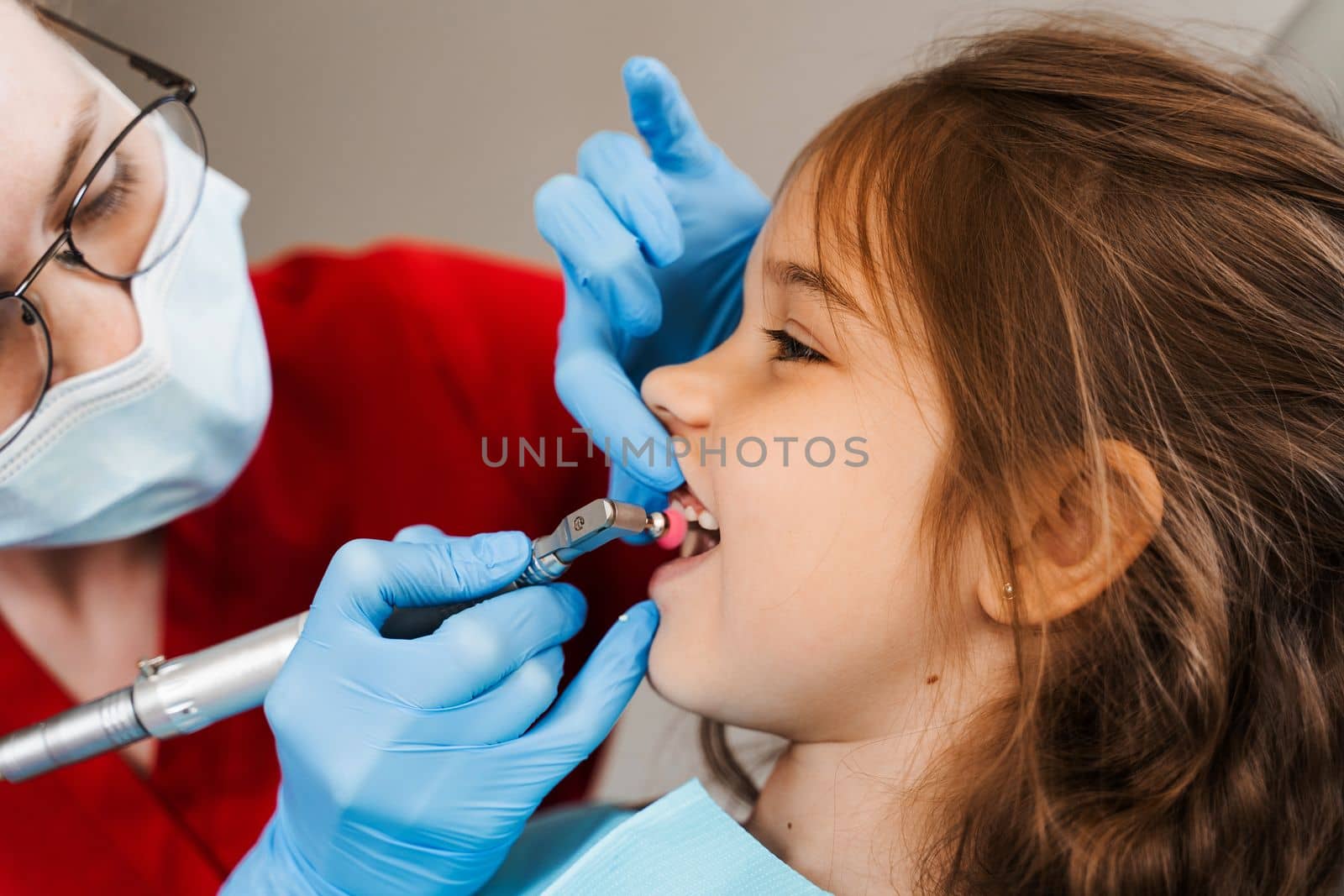 Child dentist makes professional teeth cleaning in dentistry. Professional hygiene for teeth of child in dentistry. Pediatric dentist examines and consults kid patient in dentistry