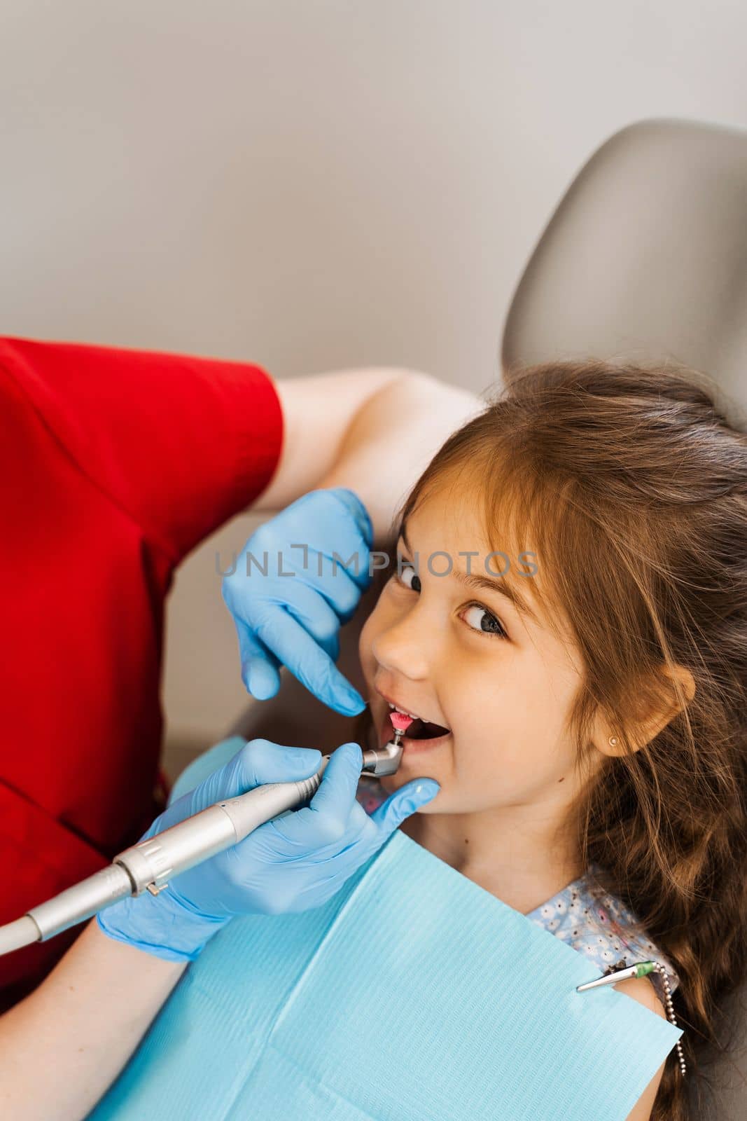 Pediatric girl dentist makes professional teeth cleaning in dentistry. Professional hygiene for teeth of child in dentistry. Pediatric dentist examines and consults kid patient in dentistry. by Rabizo