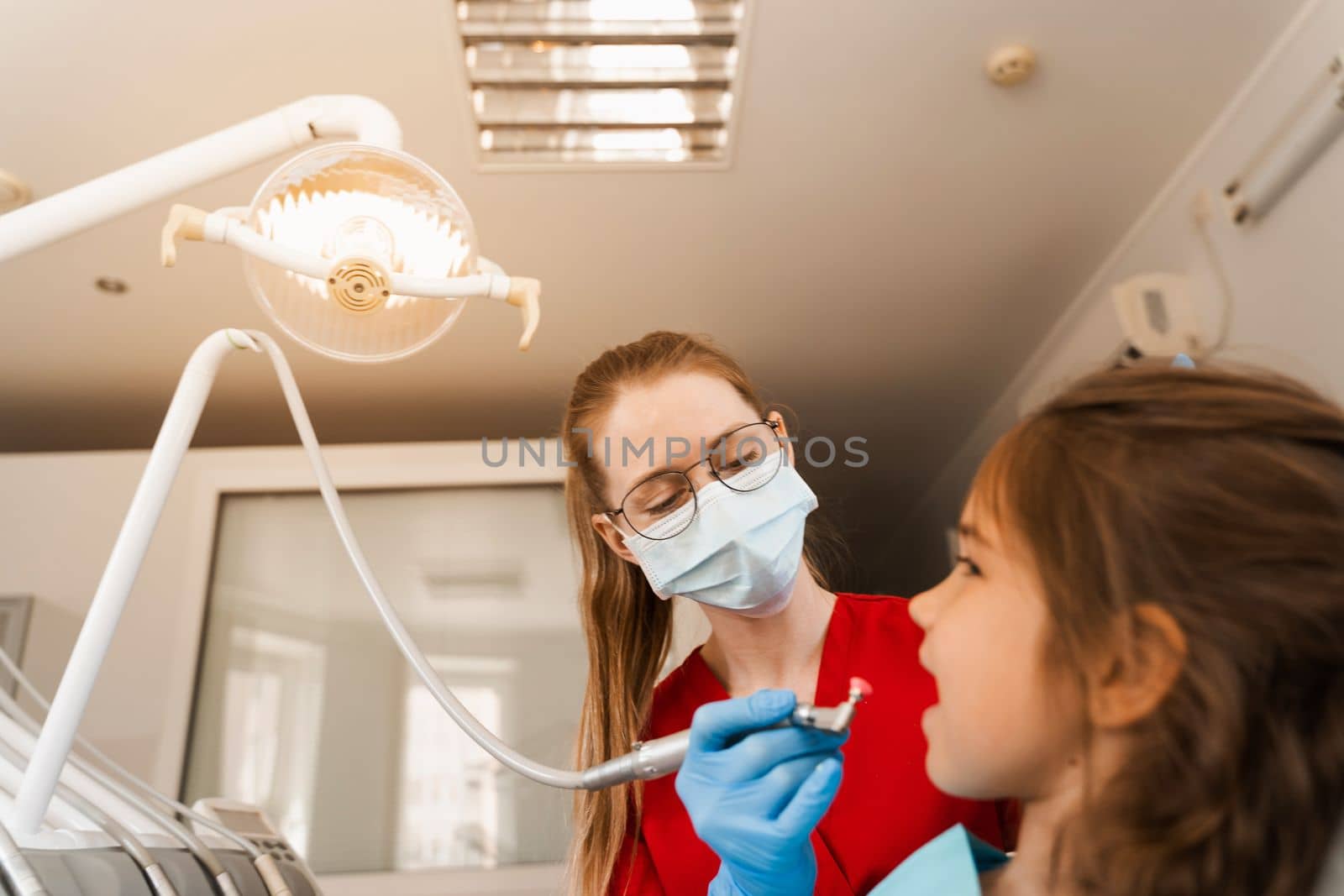 Child dentist makes professional teeth cleaning close-up in dentistry. Professional hygiene for teeth of child in dentistry. Pediatric dentist examines and consults kid patient in dentistry. by Rabizo