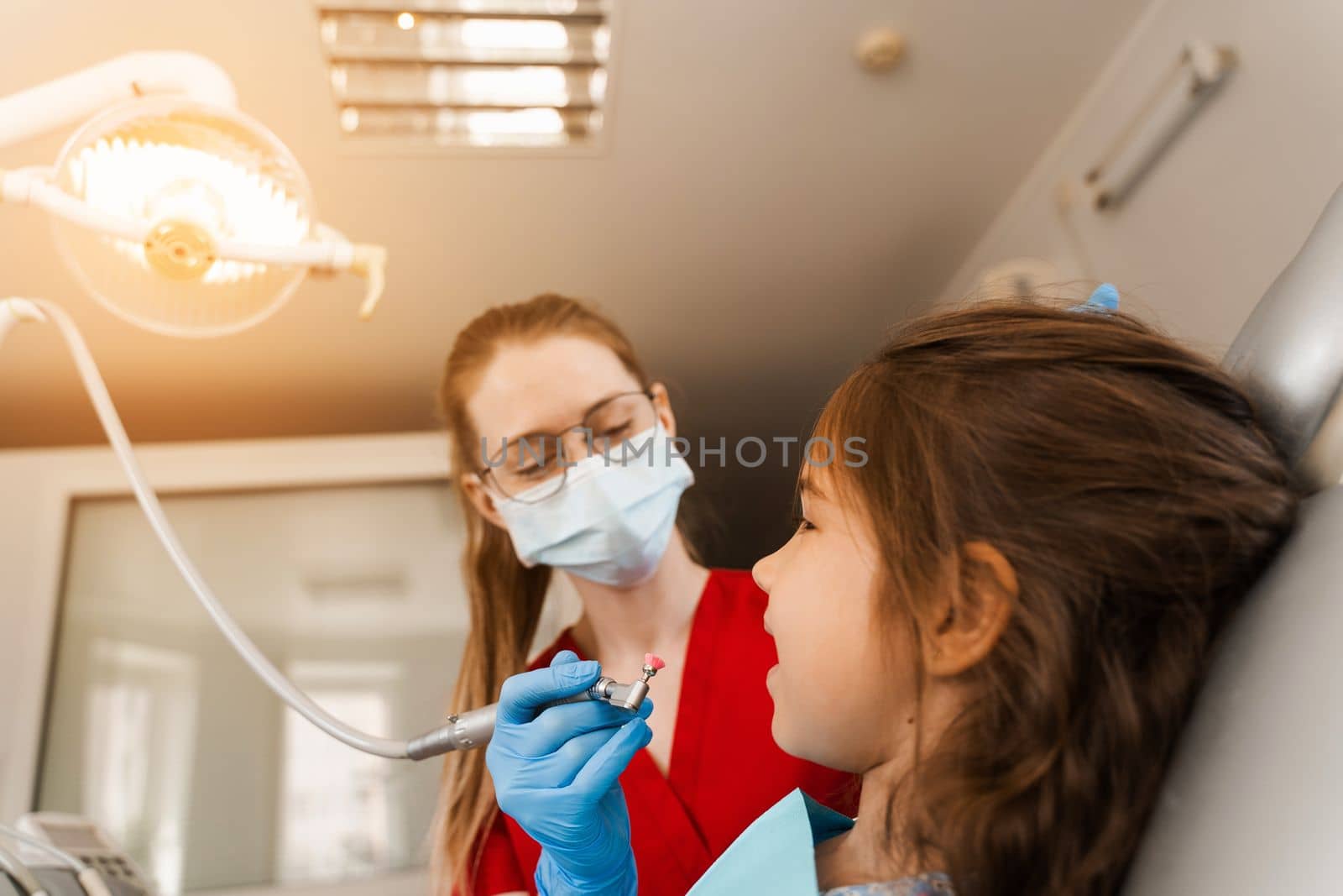 Child dentist makes professional teeth cleaning close-up in dentistry. Professional hygiene for teeth of child in dentistry. Pediatric dentist examines and consults kid patient in dentistry