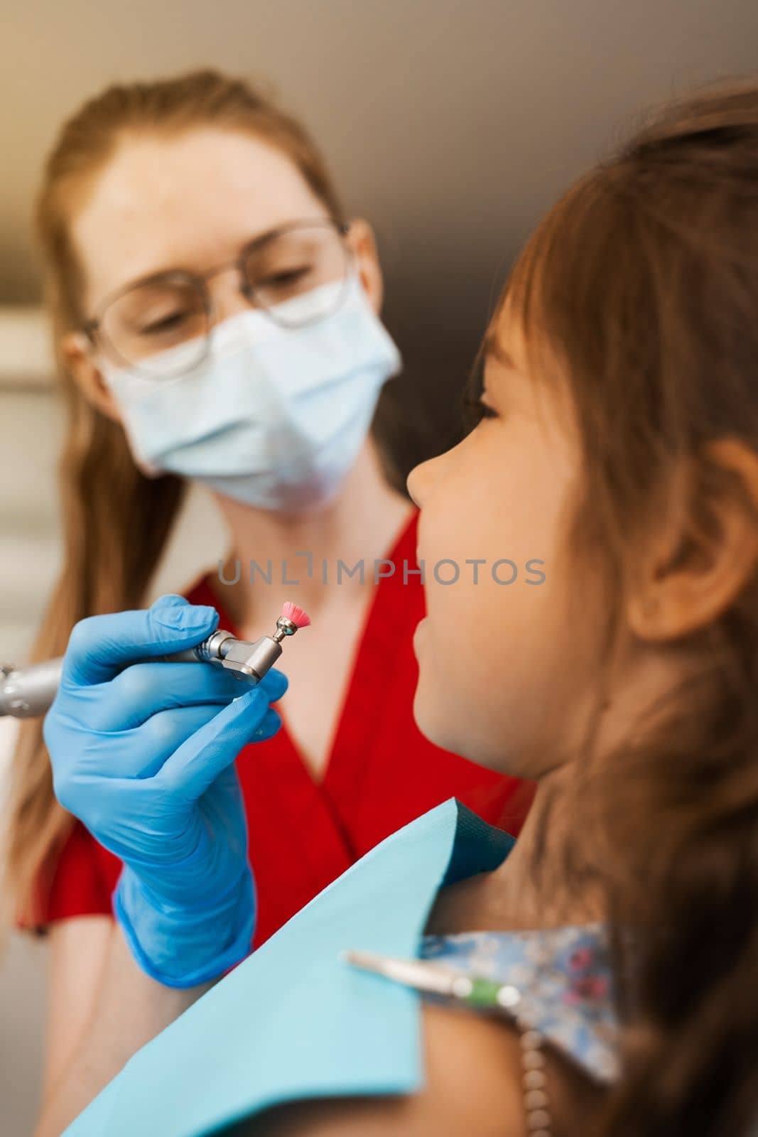 Child dentist makes professional teeth cleaning close-up in dentistry. Professional hygiene for teeth of child in dentistry. Pediatric dentist examines and consults kid patient in dentistry