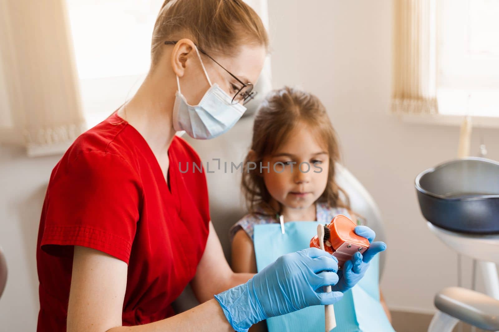 Oral hygiene lesson of jaw anatomical model for child in dentistry. Dentist shows child how to properly brush his teeth with a toothbrush. by Rabizo