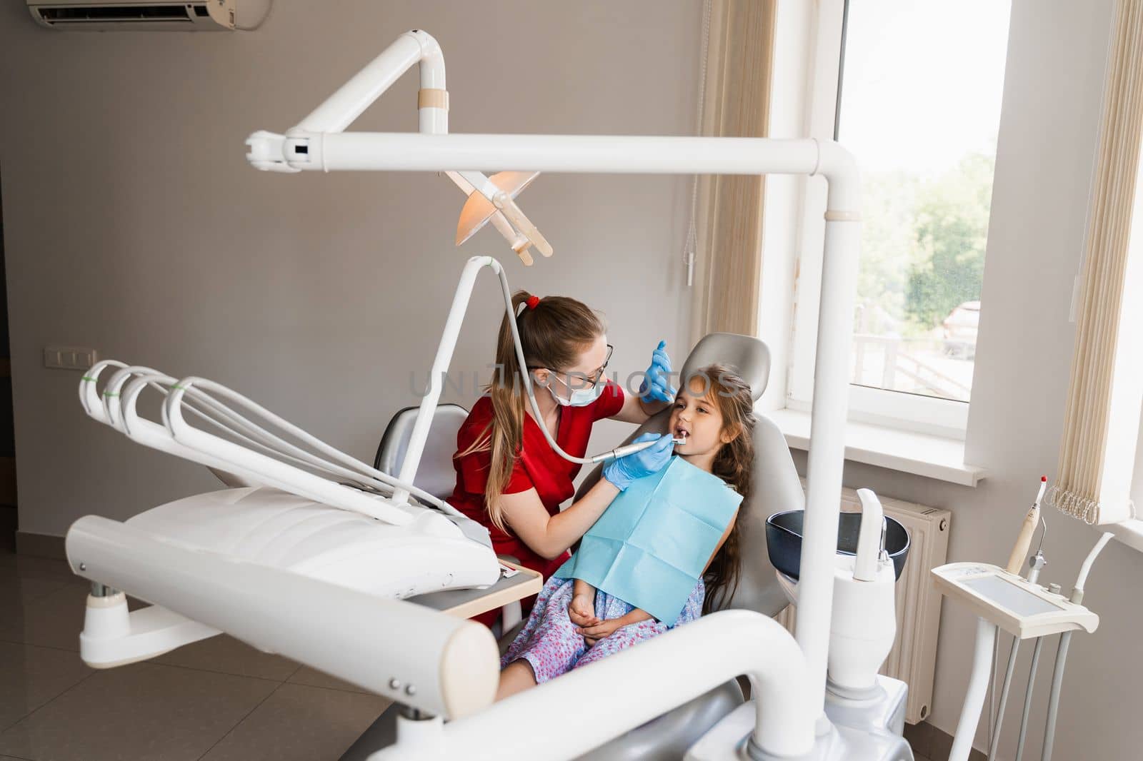 Pediatric dentist examines and consults kid patient in dentistry. Professional hygiene for teeth of child in dentistry. Professional teeth cleaning for child girl