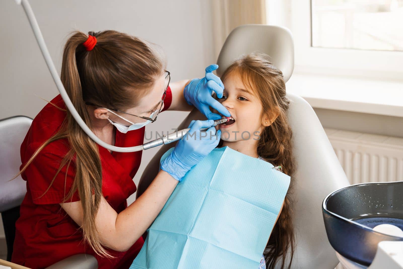 Child dentist makes professional teeth cleaning in dentistry. Professional hygiene for teeth of child in dentistry. Pediatric dentist examines and consults kid patient in dentistry