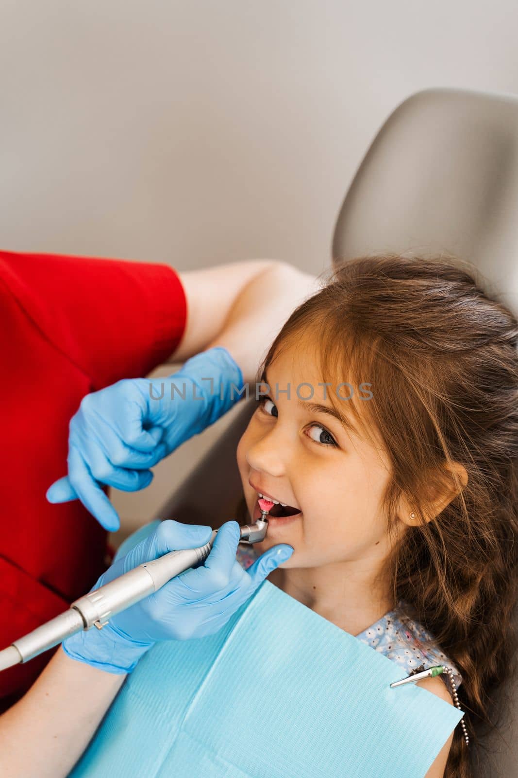 Pediatric girl dentist makes professional teeth cleaning in dentistry. Professional hygiene for teeth of child in dentistry. Pediatric dentist examines and consults kid patient in dentistry