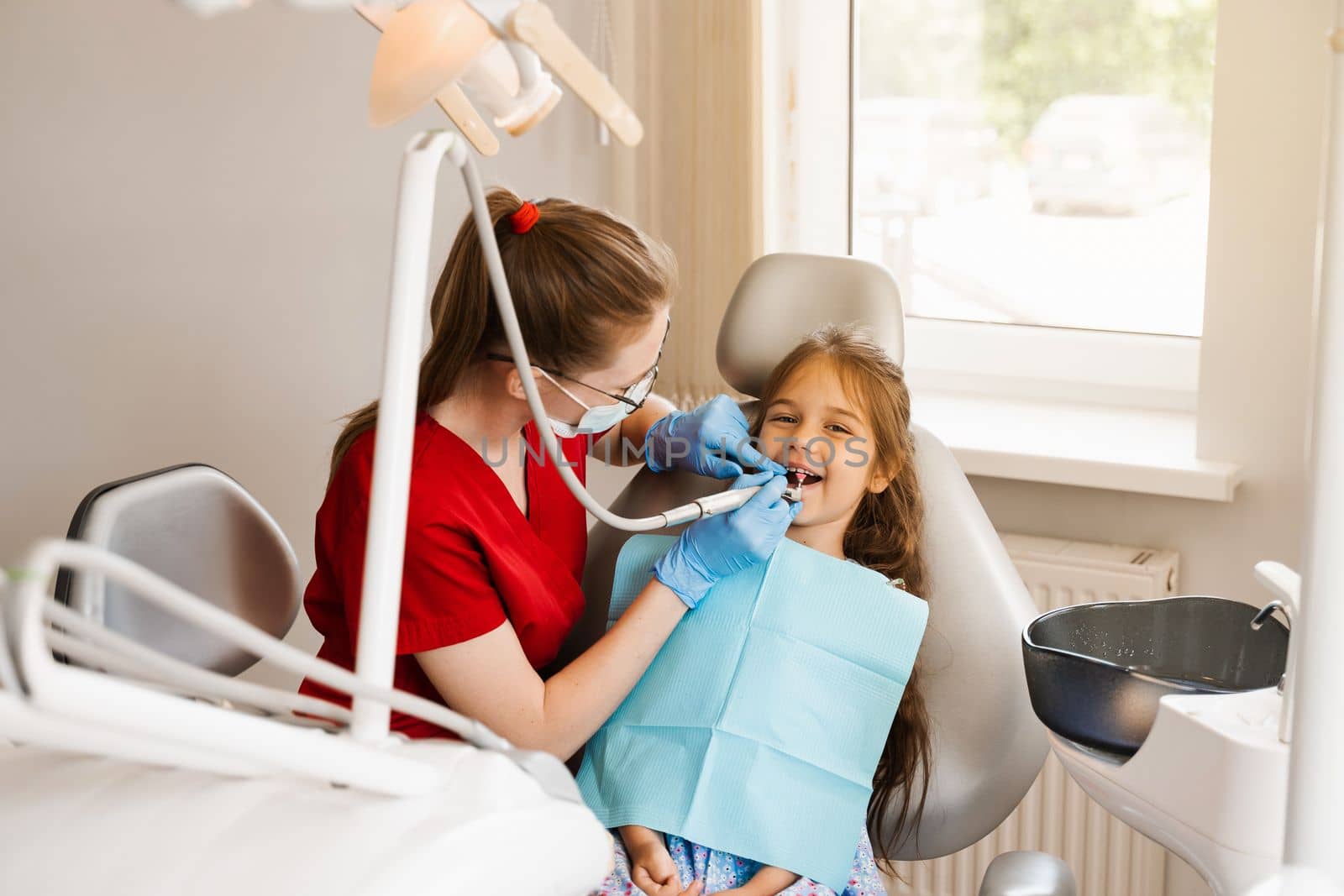 Pediatric dentist examines and consults kid patient in dentistry. Professional hygiene for teeth of child in dentistry. Professional teeth cleaning for child girl