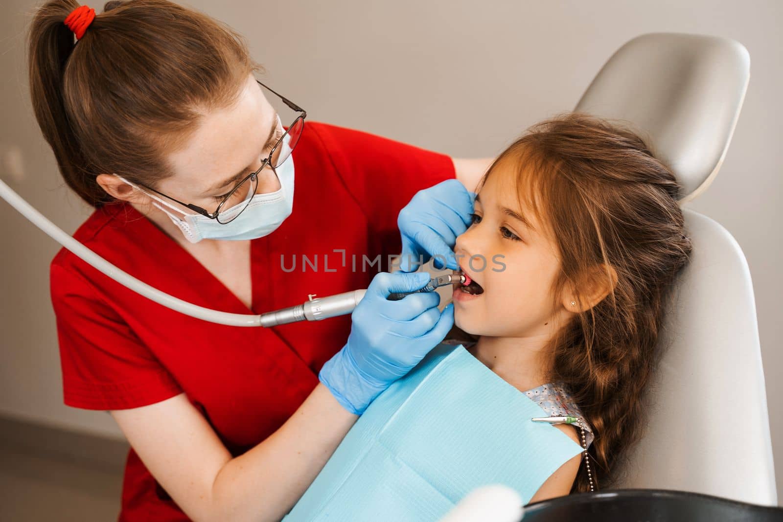 Child dentist makes professional teeth cleaning in dentistry. Professional hygiene for teeth of child in dentistry. Pediatric dentist examines and consults kid patient in dentistry