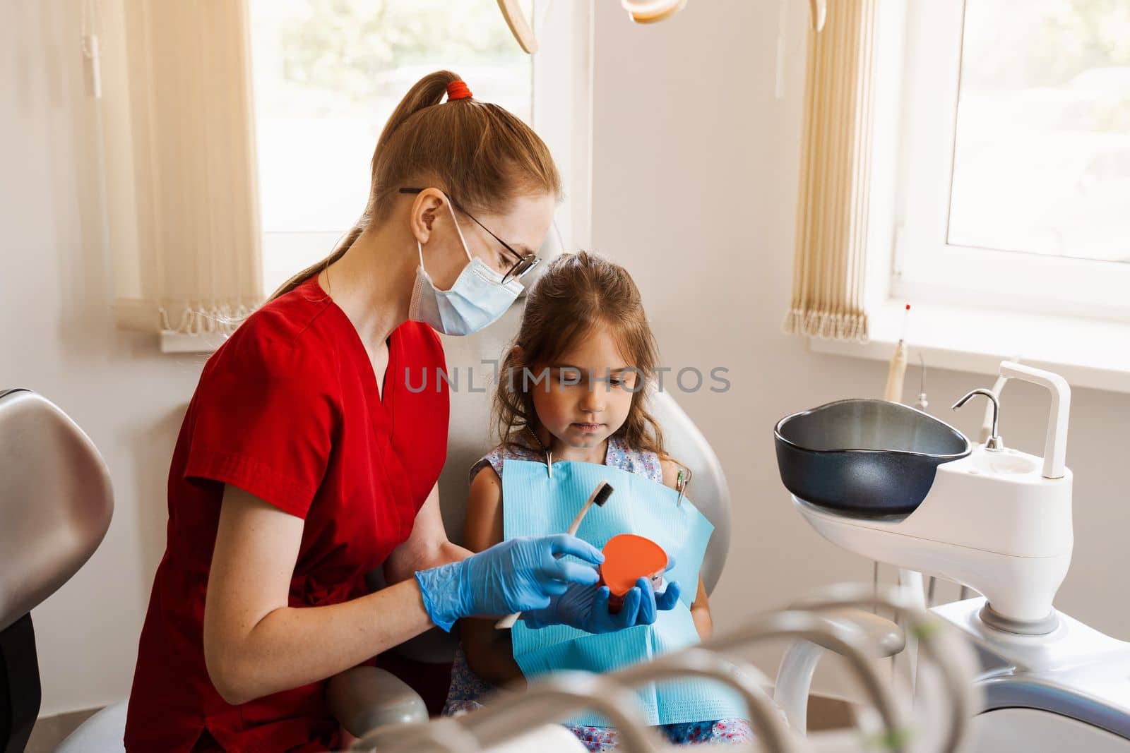 Dentist shows child how to properly use toothbrush for brush teeth. Jaw anatomical model teeth brushing. Pediatric dentist teaching oral hygiene lesson for kids in dentistry. by Rabizo