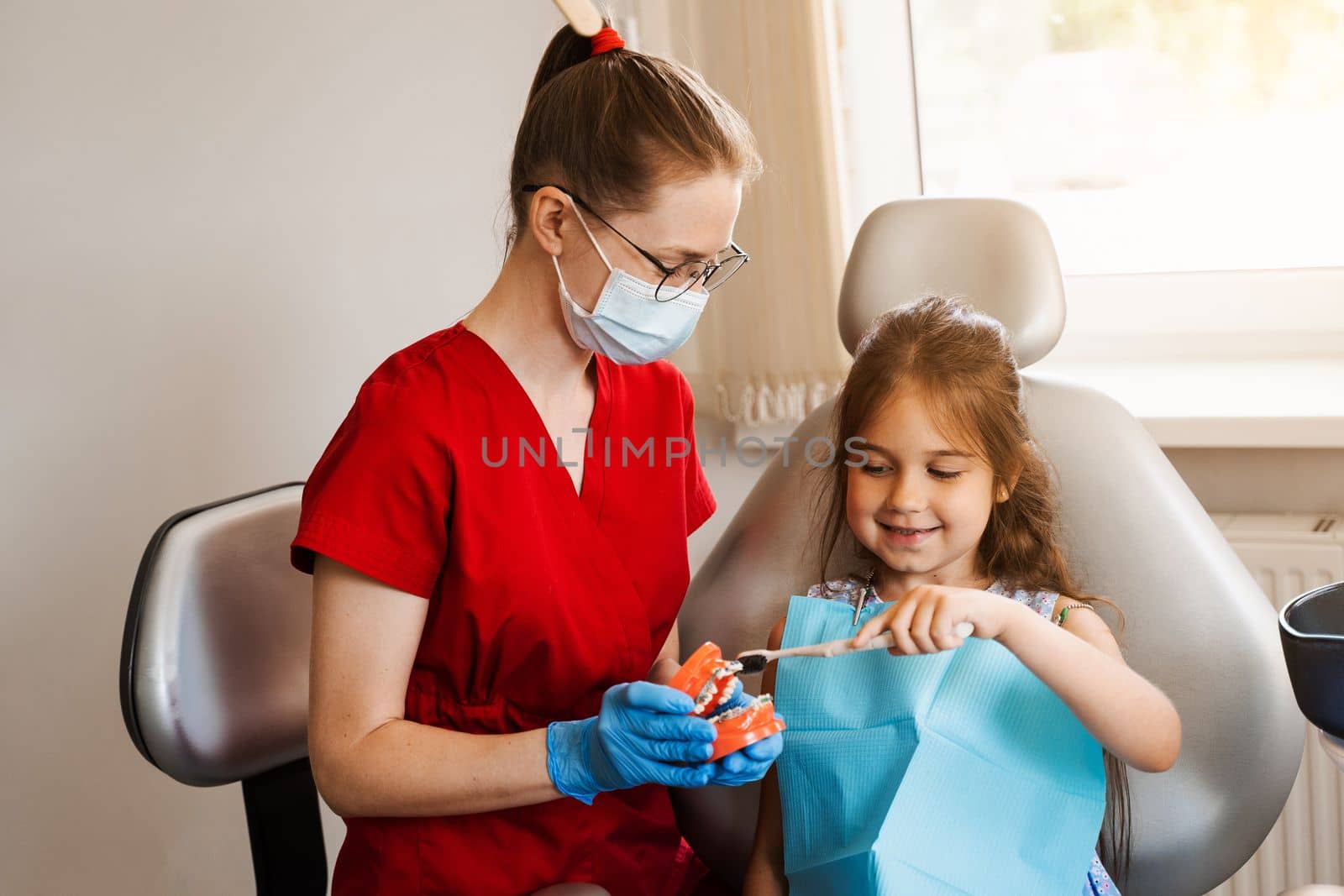 Jaw anatomical model teeth brushing. Pediatric dentist teaching oral hygiene lesson for kids in dentistry. The dentist shows child how to properly use toothbrush for brush teeth. by Rabizo