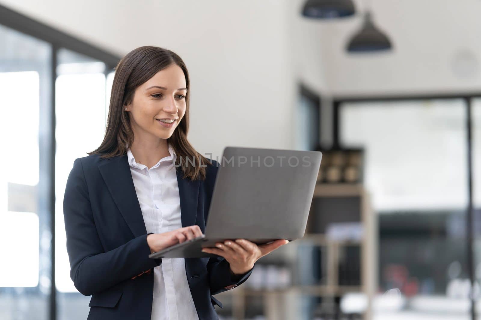 Asian young female professional businesswoman secretary employee in formal suit at working desk typing report via laptop notebook computer