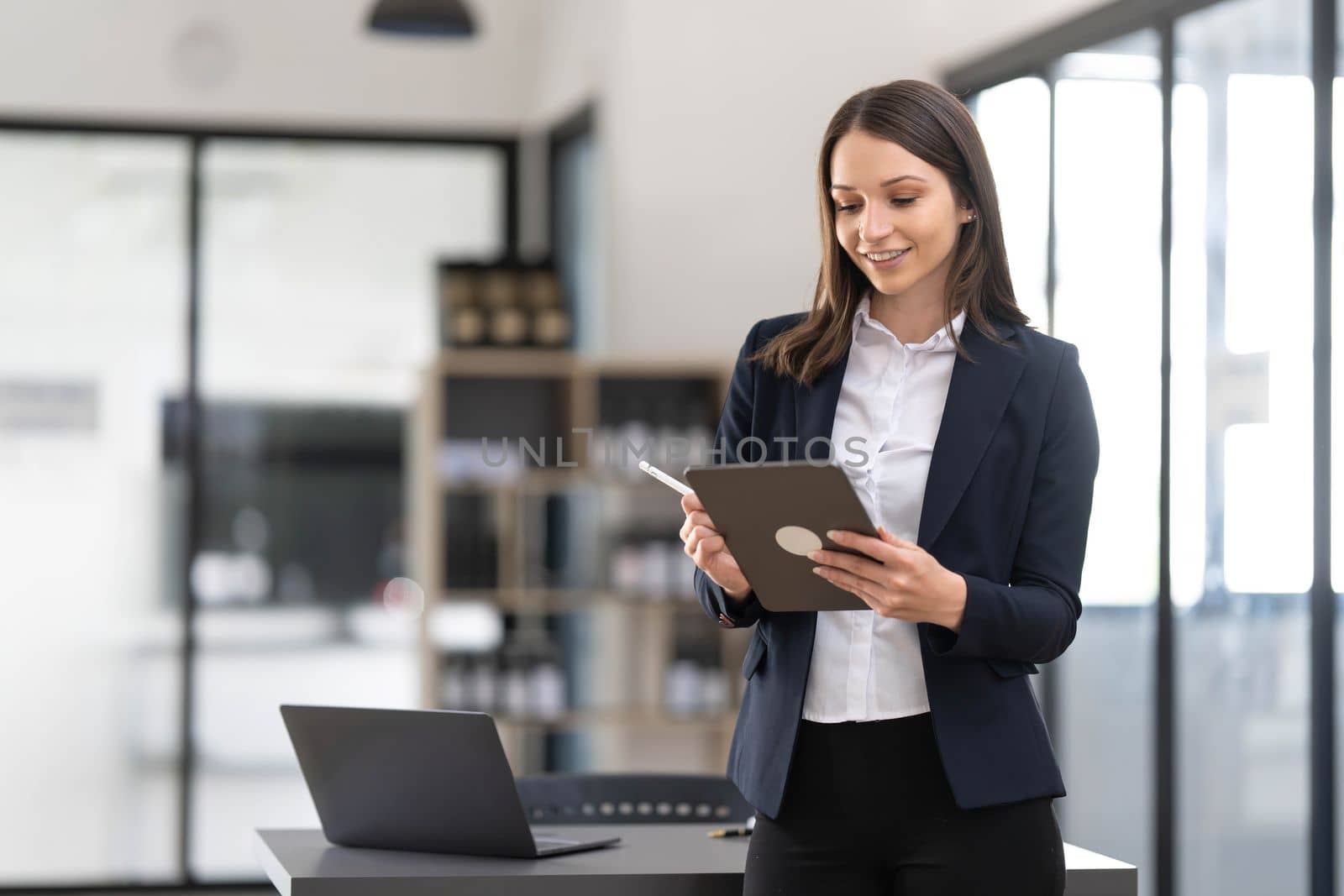 Young asian businesswoman using the tablet to analyze business data while she is standing at the office...