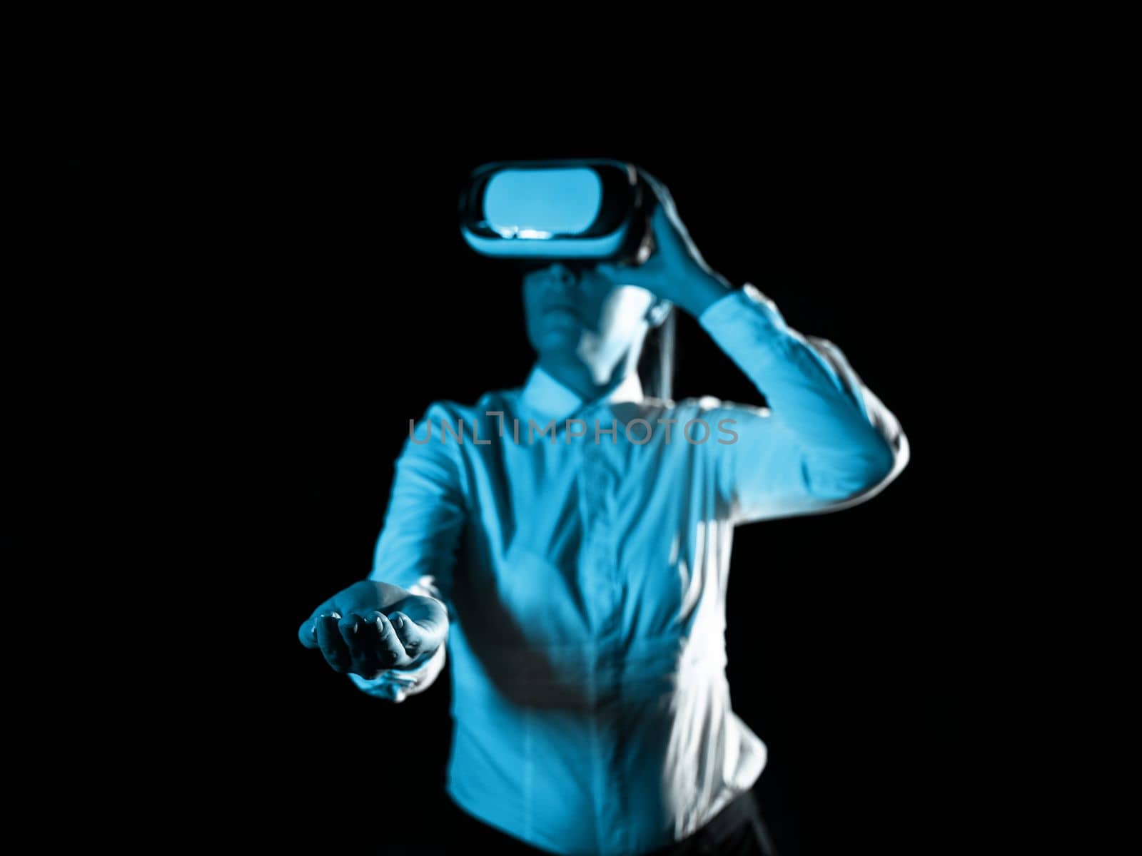 Woman Wearing Vr Glasses And hord Important Messages With one hand. Businesswoman Having Virtual Reality Eyeglasses And Showing Crutial Informations. by nialowwa