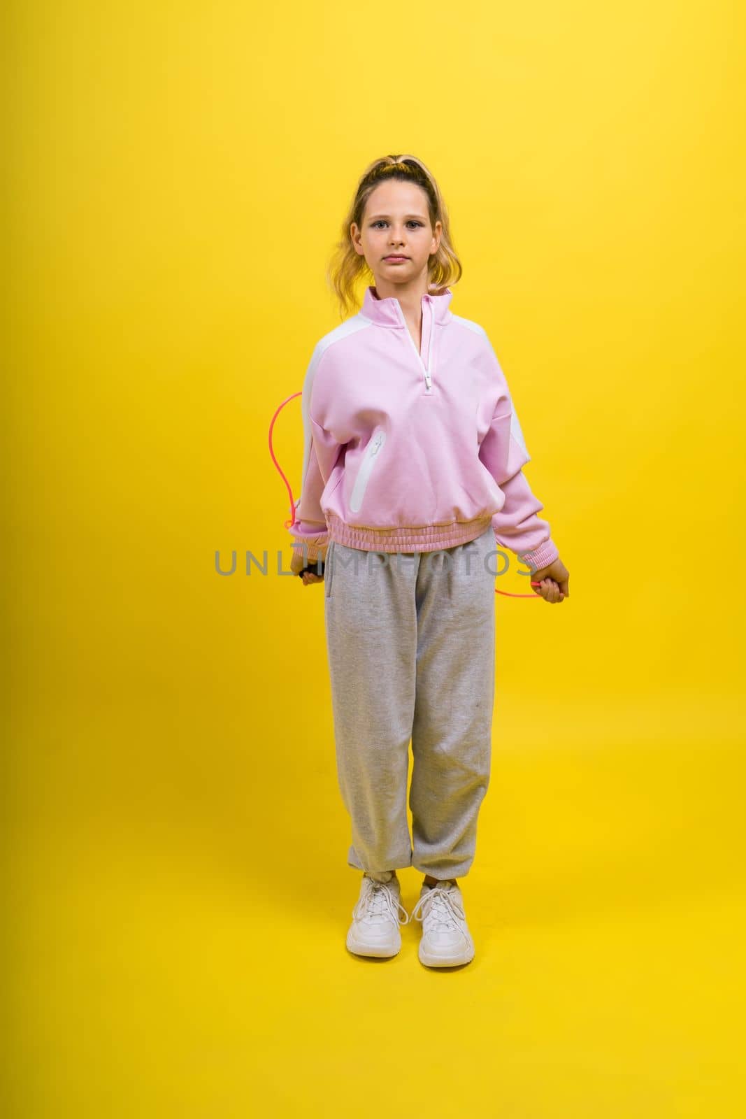 Adorable female child with skipping rope jumping in studio by Zelenin