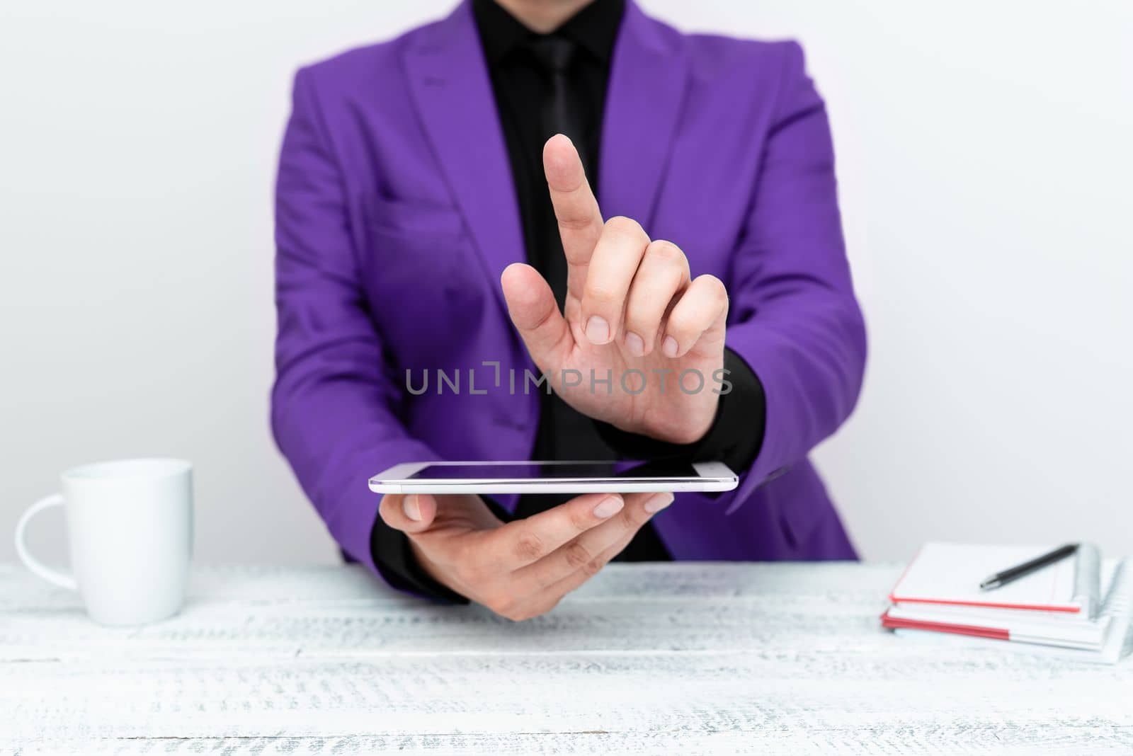 Businessman in Purple jacket sitting at table holding mobile phone And Pointing With One Finger On Important Message. Gentleman Showing Critical Announcement. by nialowwa