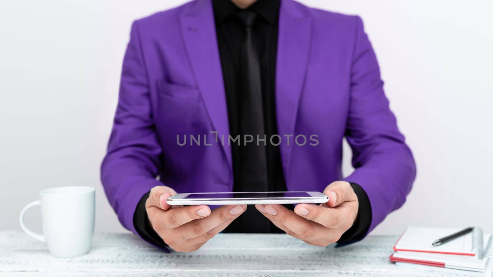 Businessman in Purple jacket sitting at table and holding mobile phone. Presenting an important message. Executive In Suit Presenting Crutial Information. by nialowwa