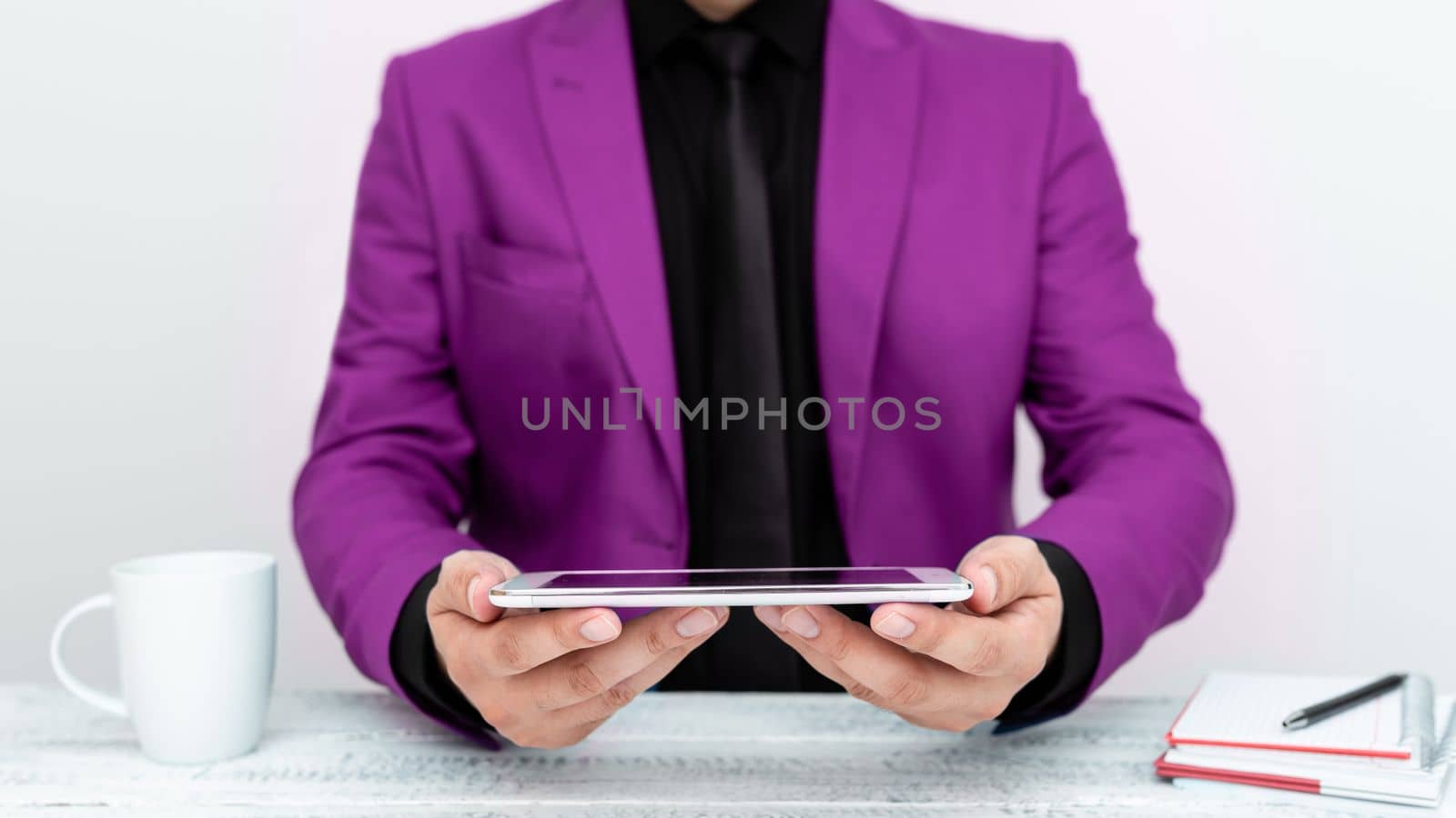 Businessman in Pink jacket sitting at table and holding mobile phone. Presenting an important message. Executive In Suit Presenting Crutial Information. by nialowwa