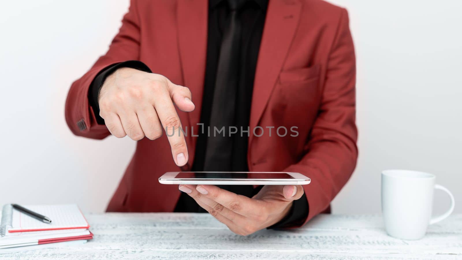 Businessman in a Red jacket sitting at a table holding a mobile phone