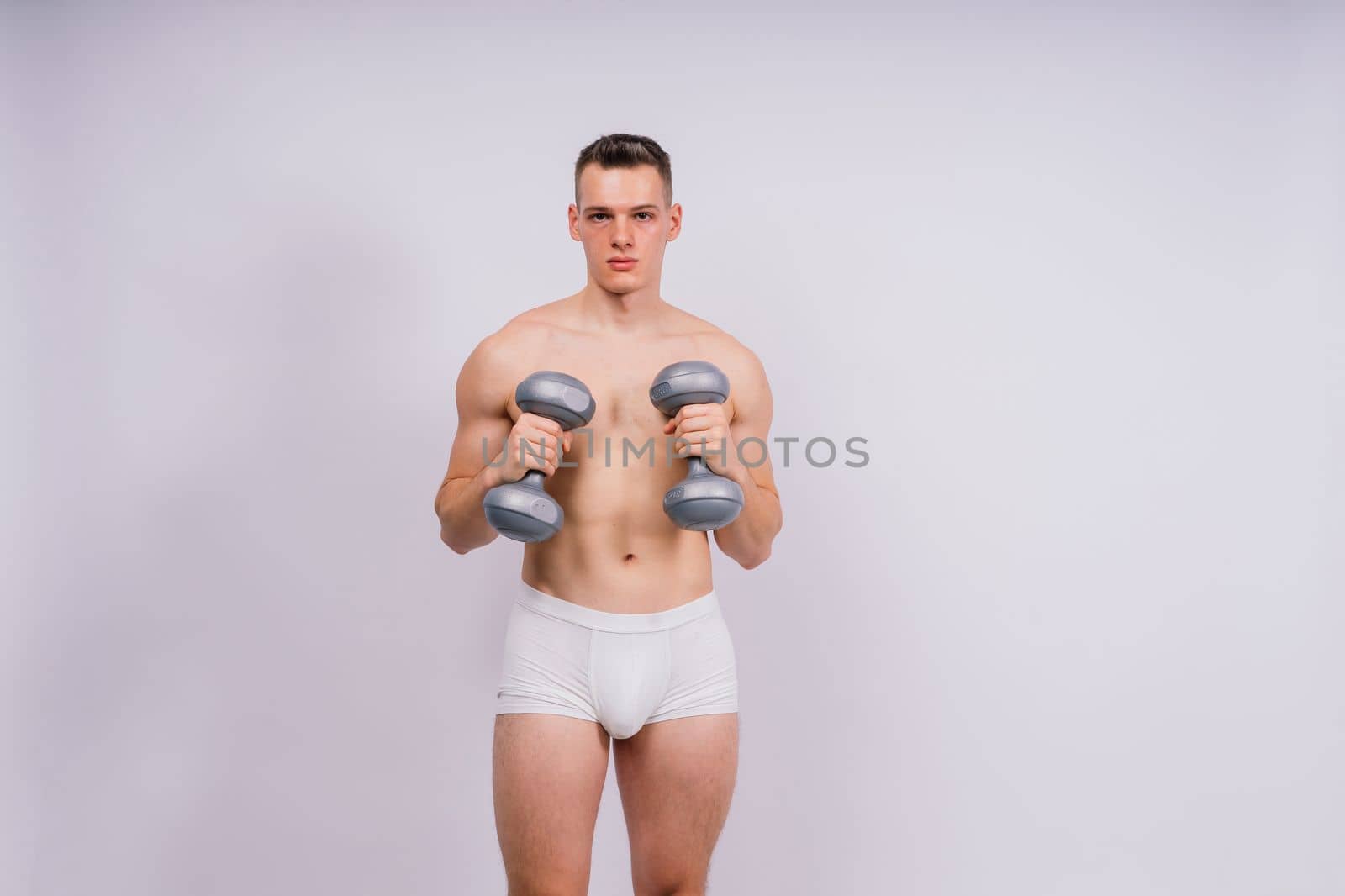 Shirtless bodybuilder holding dumbell and showing his muscular arms. by Zelenin