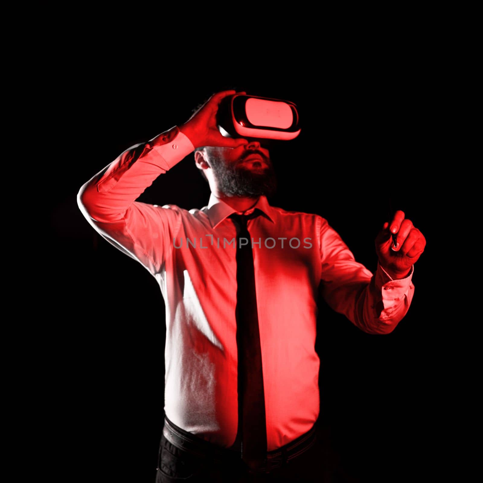 Standig Man Holding Pen To Point Important Messages And Wearing Vr Glasses. Businessman Having Virtual Reality Eyeglasses And Pointing On Crutial Informations. by nialowwa