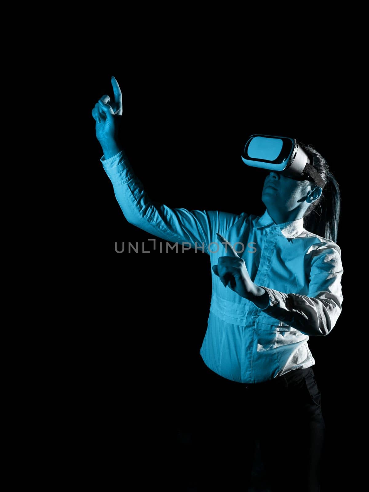 Woman Wearing Vr Glasses And Pointing On Important Messages With One Finger. Businesswoman Having Virtual Reality Eyeglasses And Showing Crutial Informations. by nialowwa