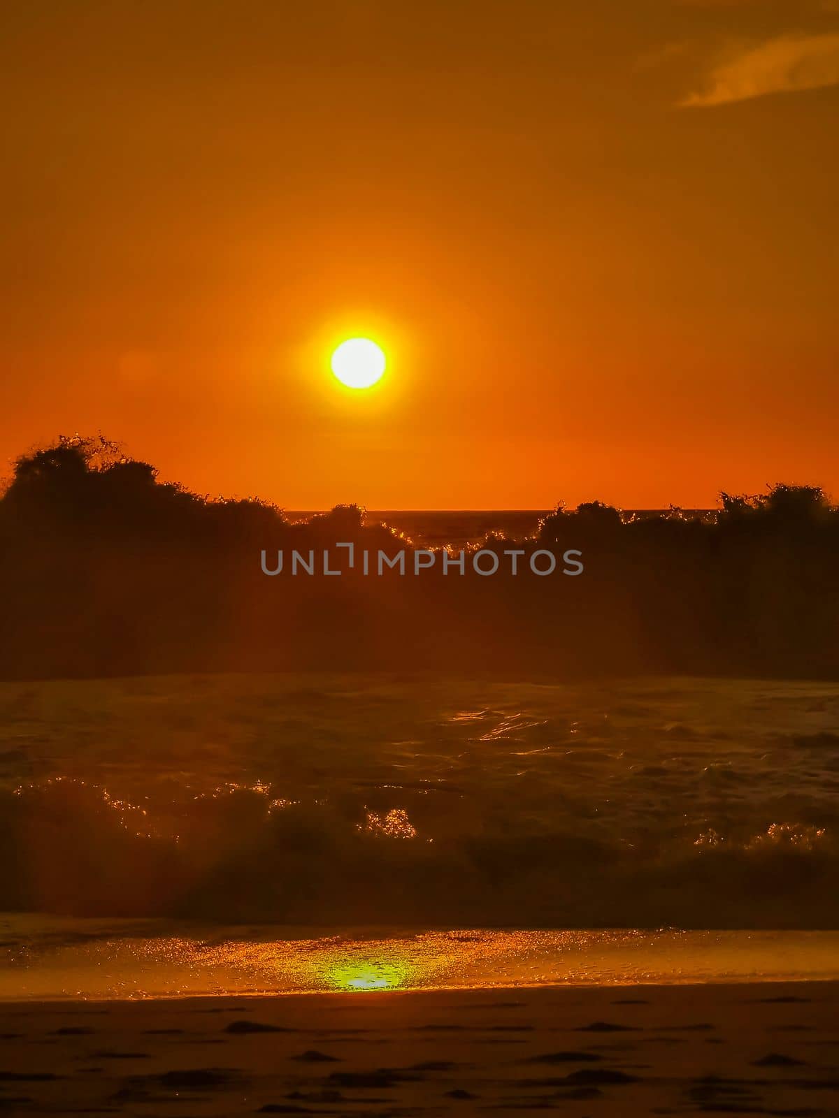 Beautiful stunning colorful and golden sunset in yellow orange red on beach and big wave panorama in tropical nature in Zicatela Puerto Escondido Oaxaca Mexico.