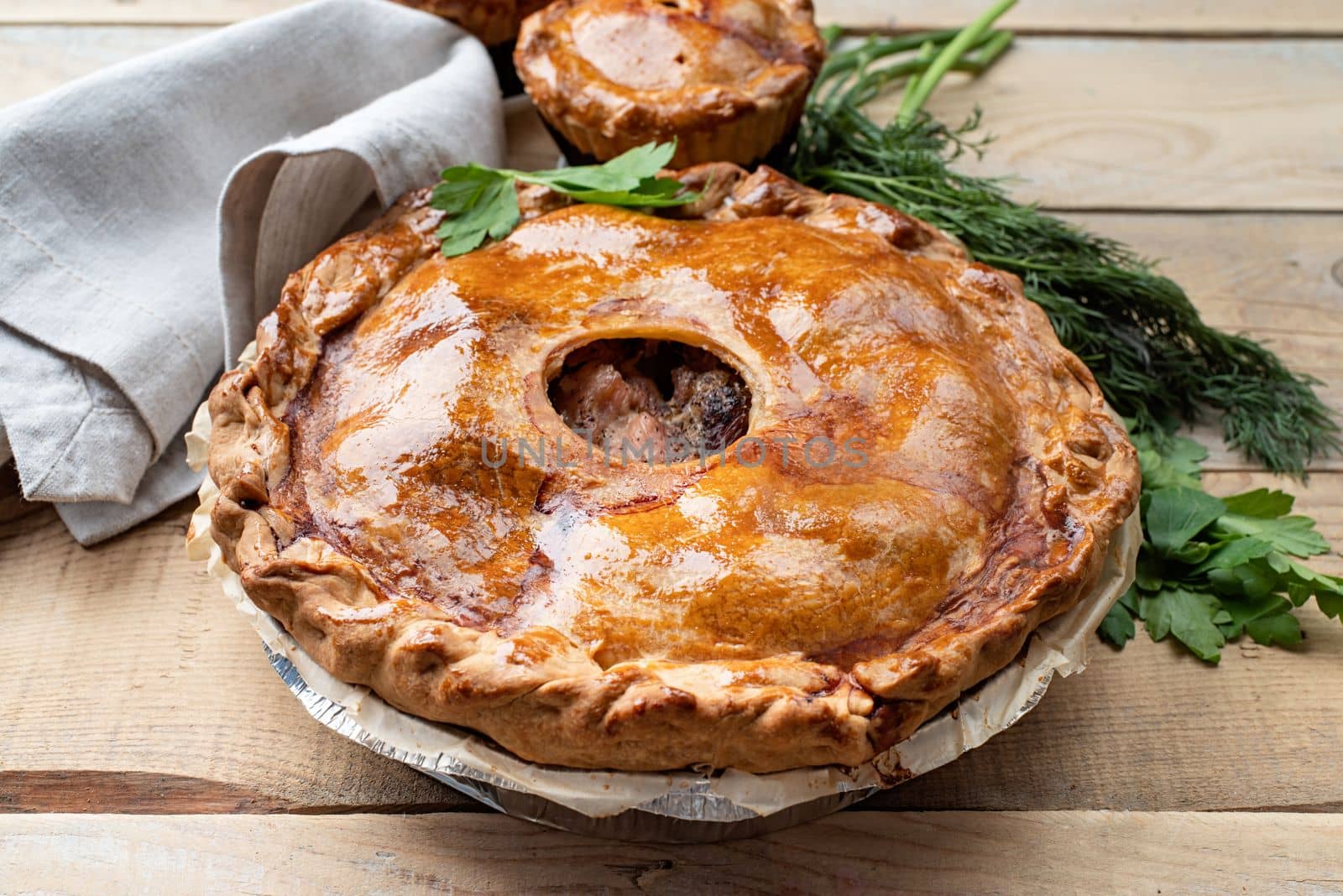Autumn food. Homemade meat pie with greenery on wooden table