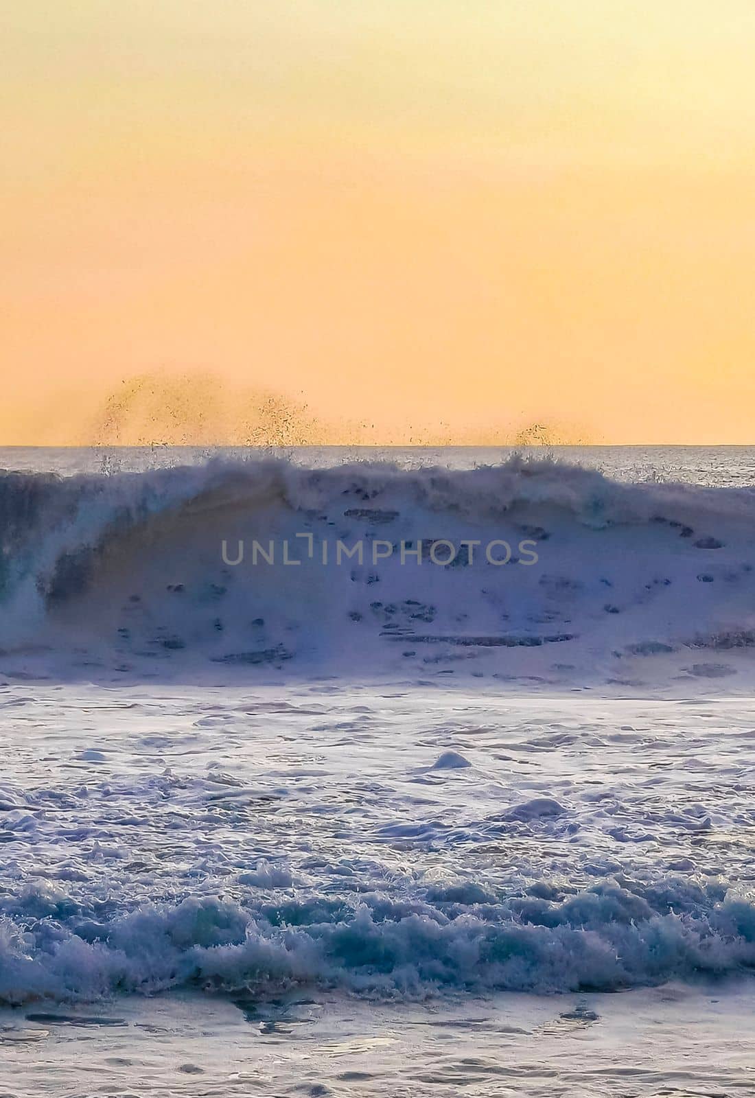 Beautiful stunning colorful and golden sunset in yellow orange red on beach and big wave panorama in tropical nature in Zicatela Puerto Escondido Oaxaca Mexico.