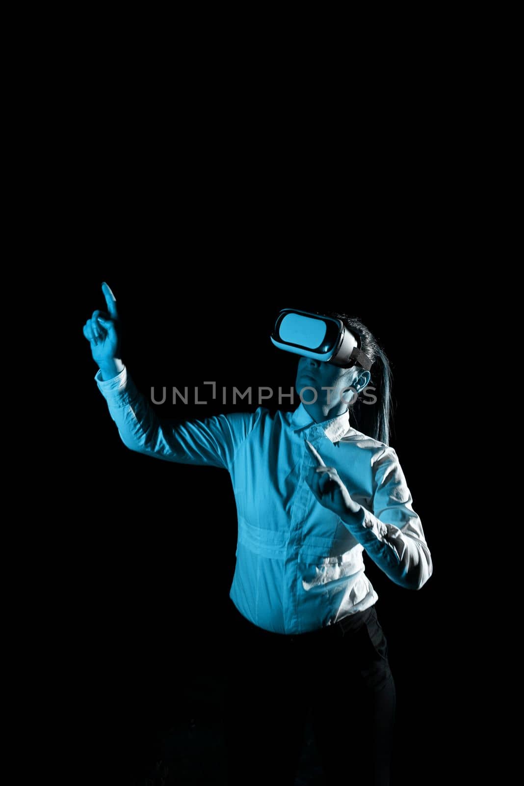 Woman Wearing Vr Glasses And Pointing On Important Messages With One Finger. Businesswoman Having Virtual Reality Eyeglasses And Showing Crutial Informations. by nialowwa
