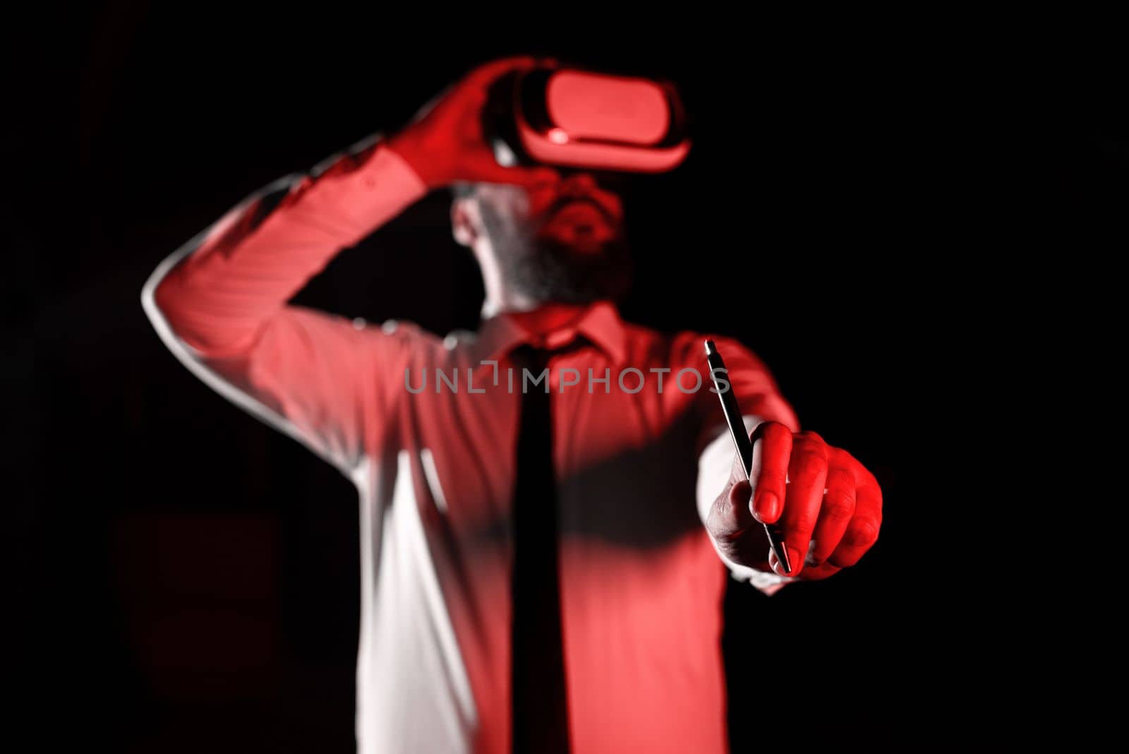 Standig Man Holding Pen To Point Important Messages And Wearing Vr Glasses. Businessman Having Virtual Reality Eyeglasses And Pointing On Crutial Informations. by nialowwa